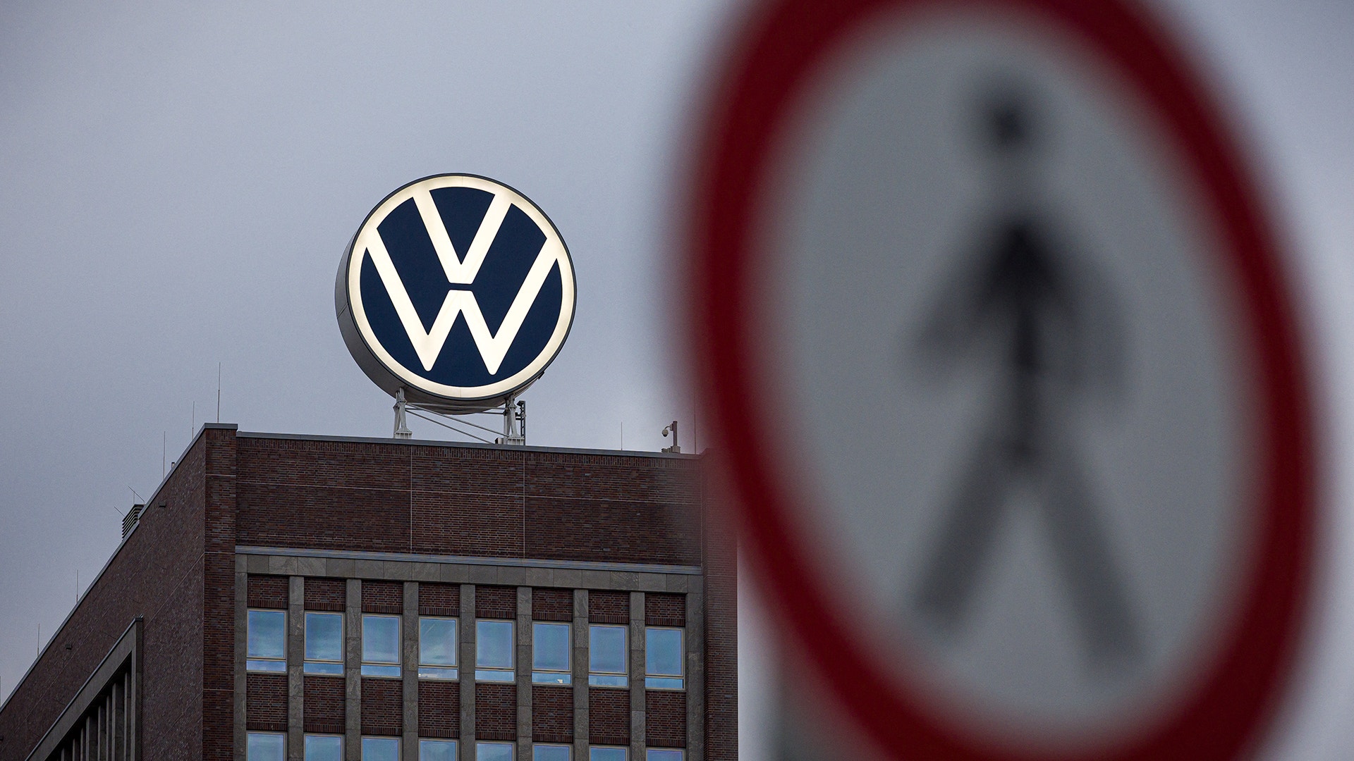 Volkswagens logotyp på taket av en byggnad, med en skylt i förgrunden.