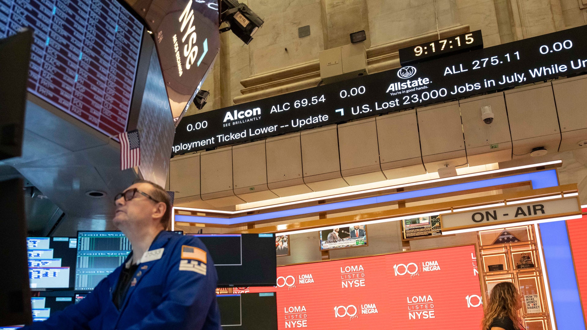Handelsgolvet på New York Stock Exchange med elektroniska prisvisningar och traders i blåa uniformer.