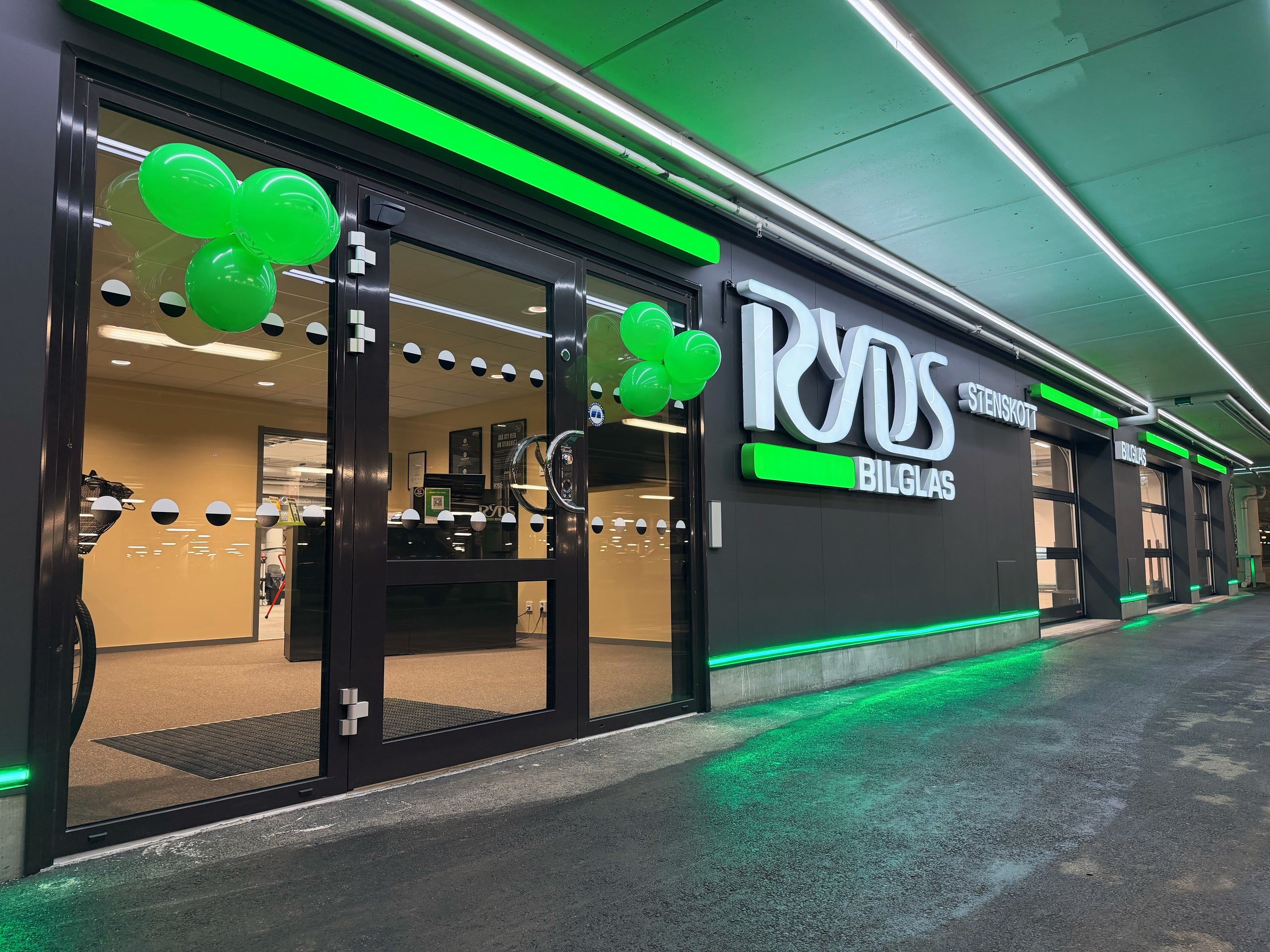 Entrén till en butik för Ryds Bilglas, dekorerad med grön neonbelysning och gröna ballonger.