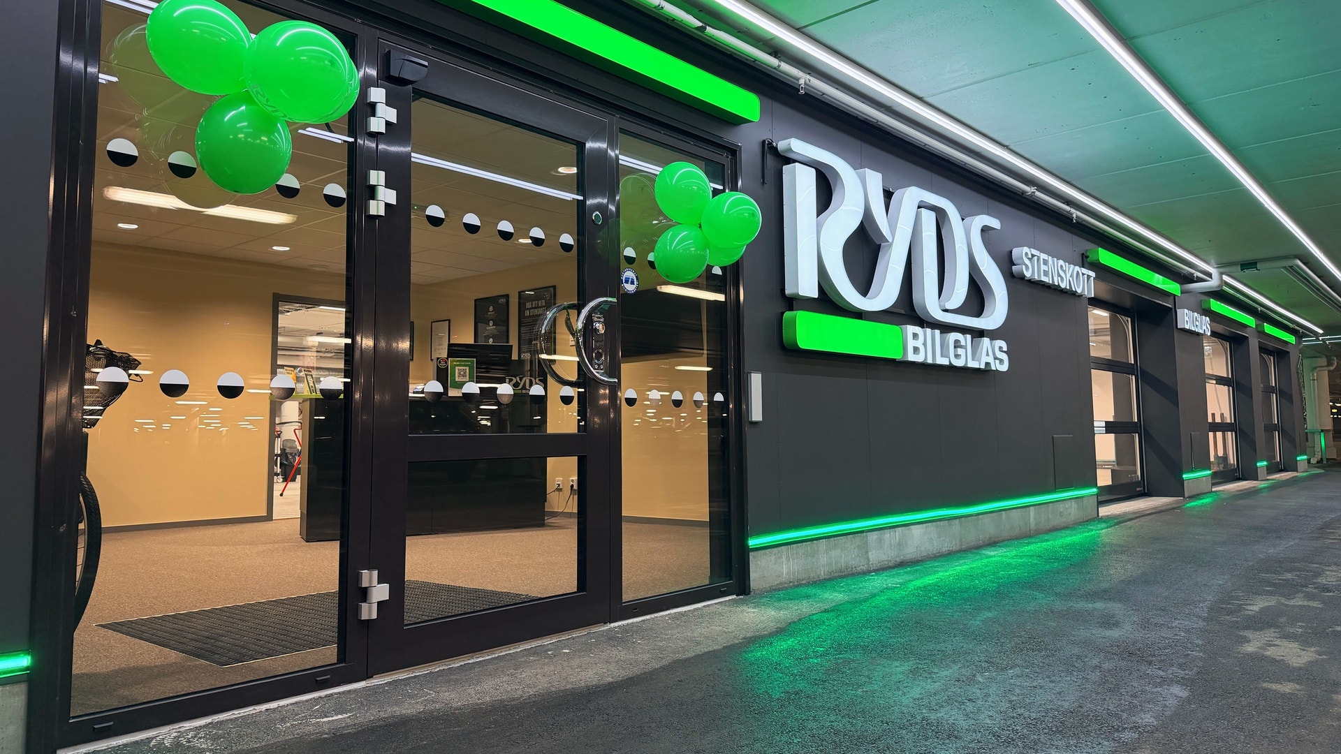 Entrén till en butik för Ryds Bilglas, dekorerad med grön neonbelysning och gröna ballonger.
