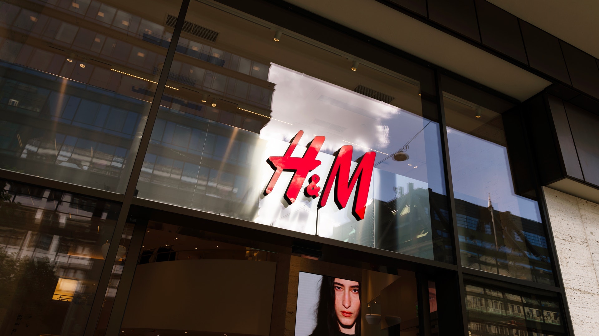 H&M-butikens fasad med röd logotyp på upplyst skylt