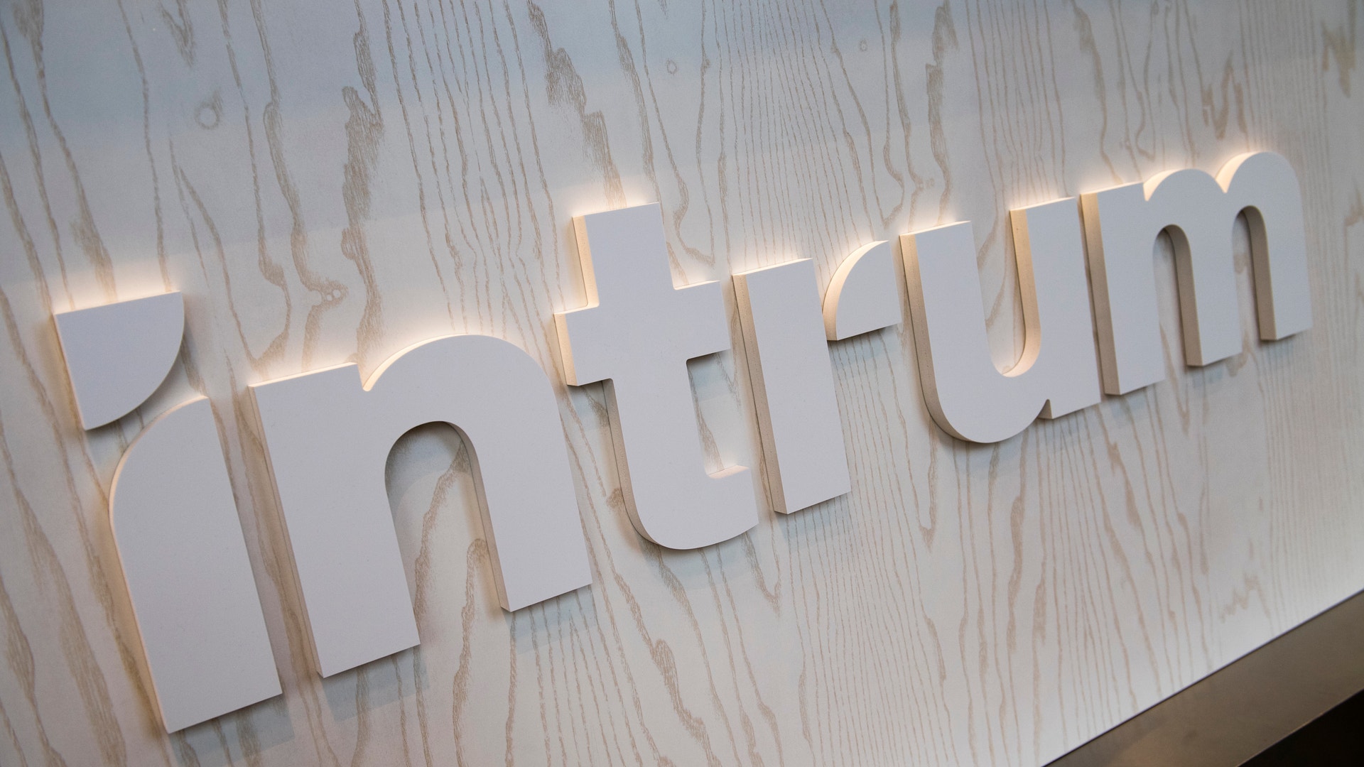 Upplysta vita bokstäver som bildar ordet "Objectic" på en ljus trävägg med bakgrundsbelysning