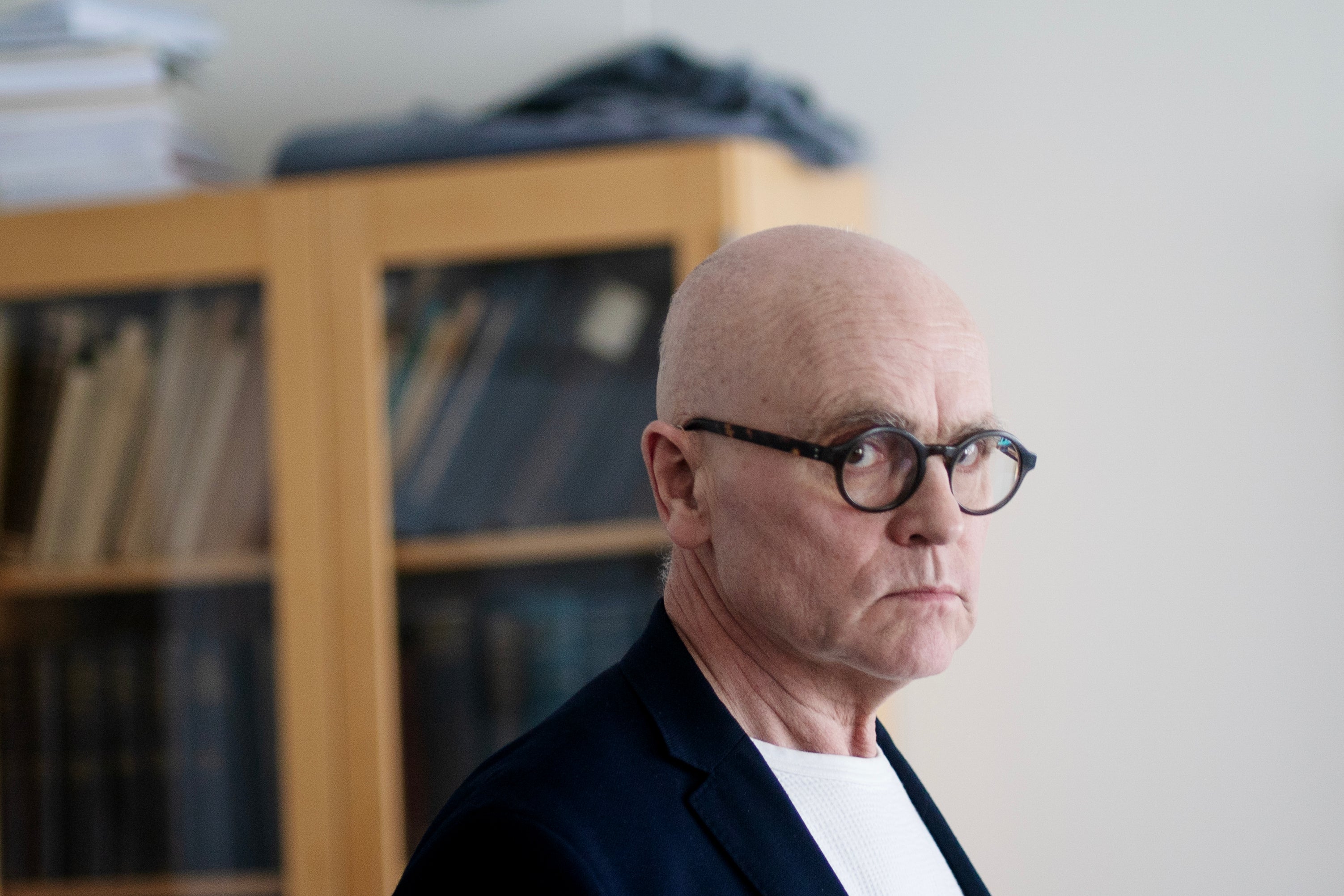 Porträtt av en man med glasögon och mörk kavaj framför en bokhylla