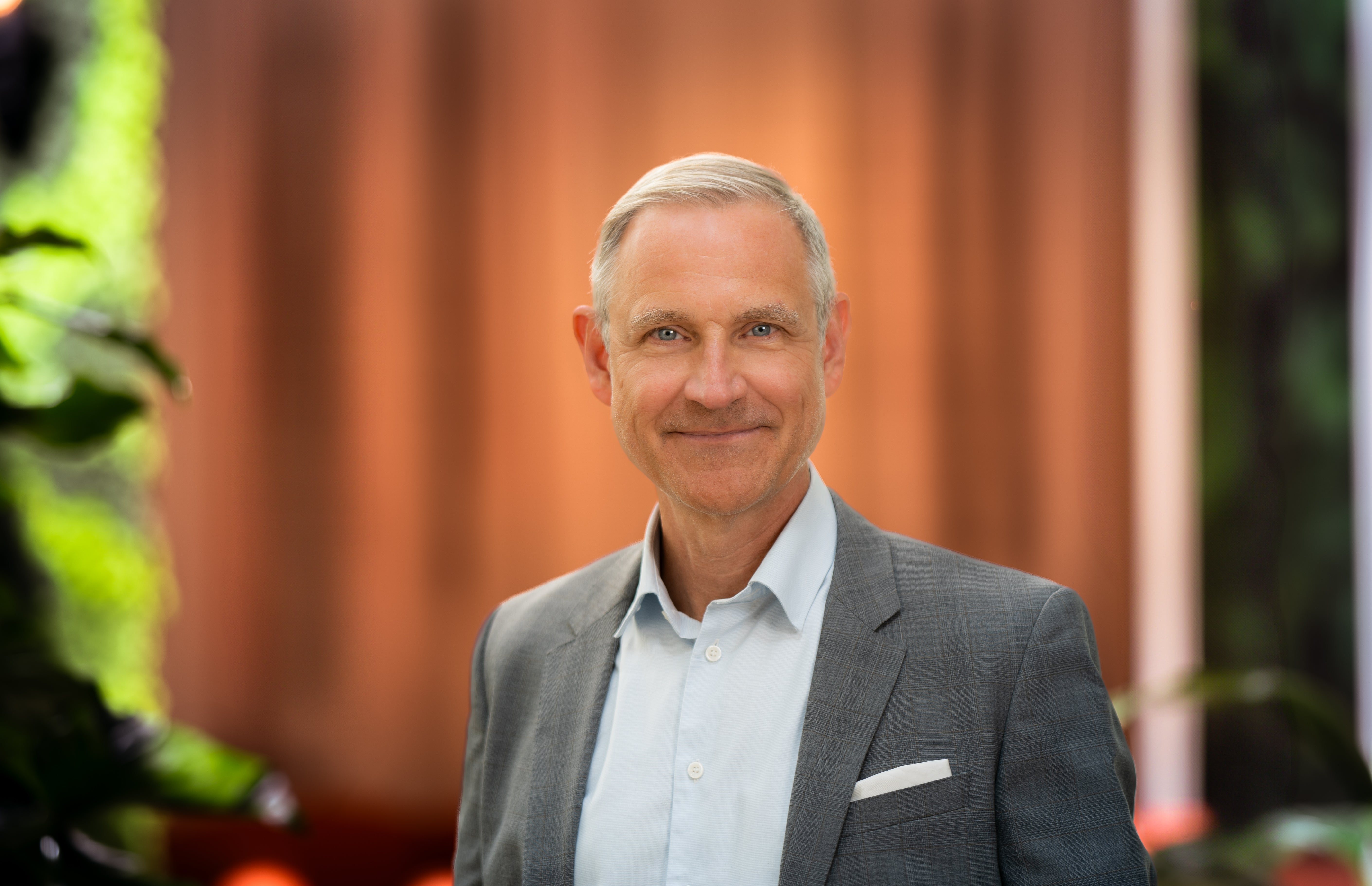 Porträtt av en medelålders man i kavaj som ler mot kameran.