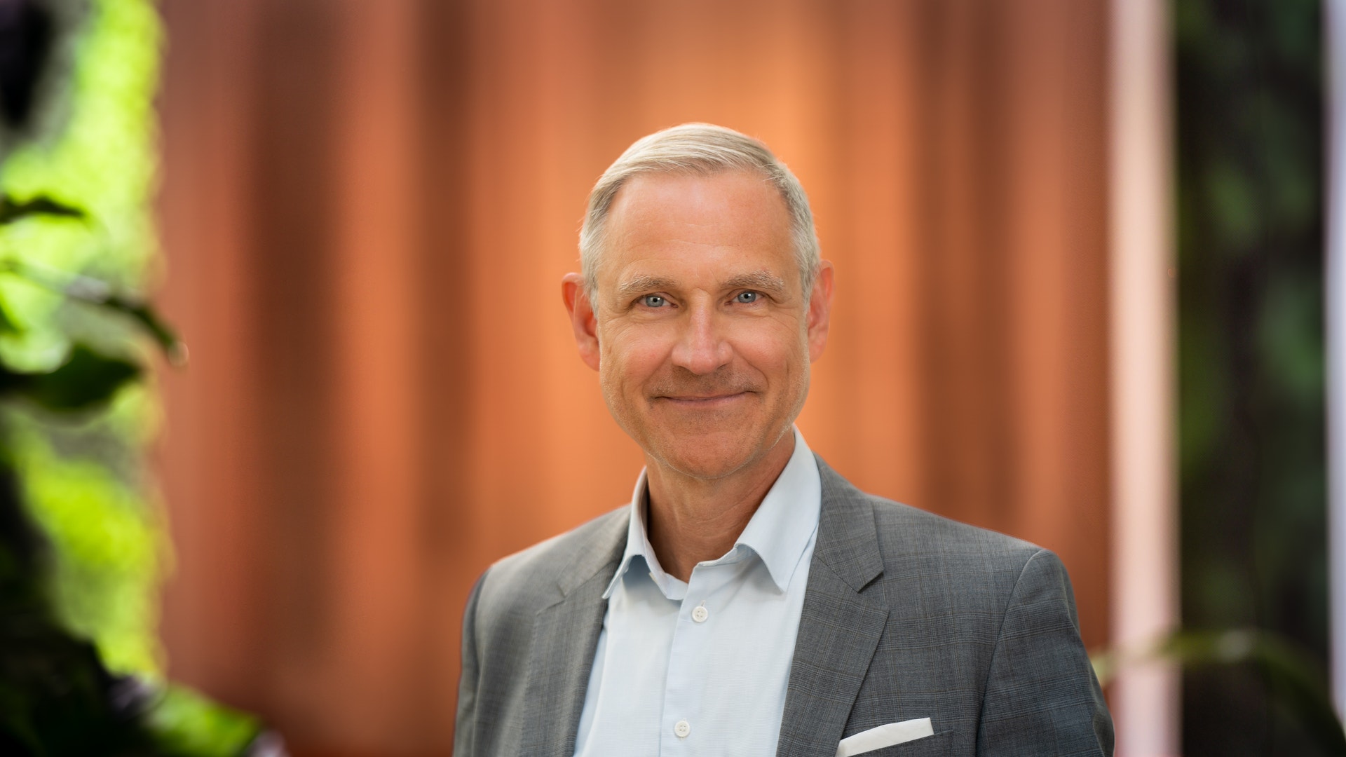 Porträtt av en medelålders man i kavaj som ler mot kameran.