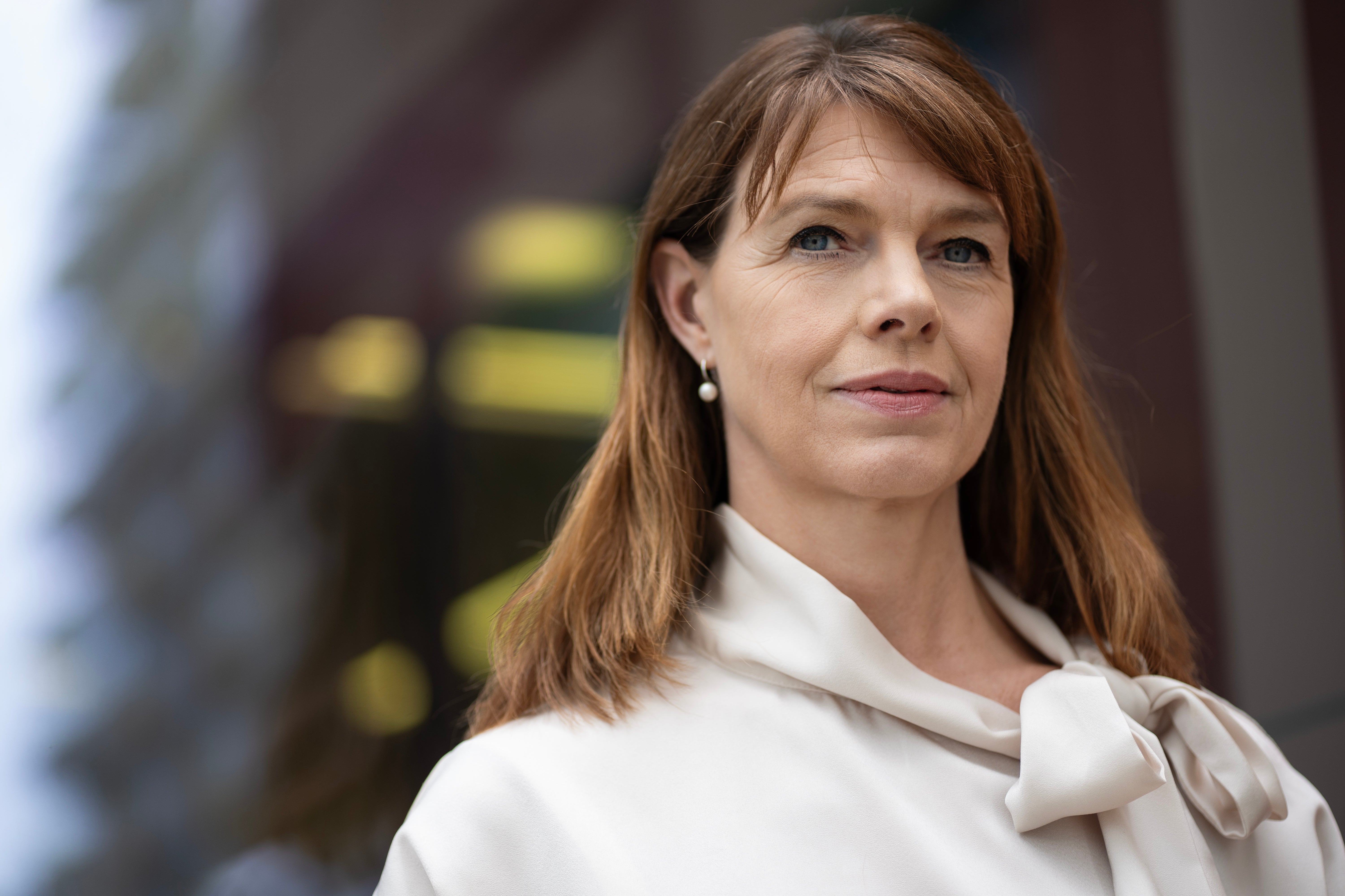Porträtt av en kvinnlig person med långt rödbrunt hår, klädd i vit skjorta med rosett.