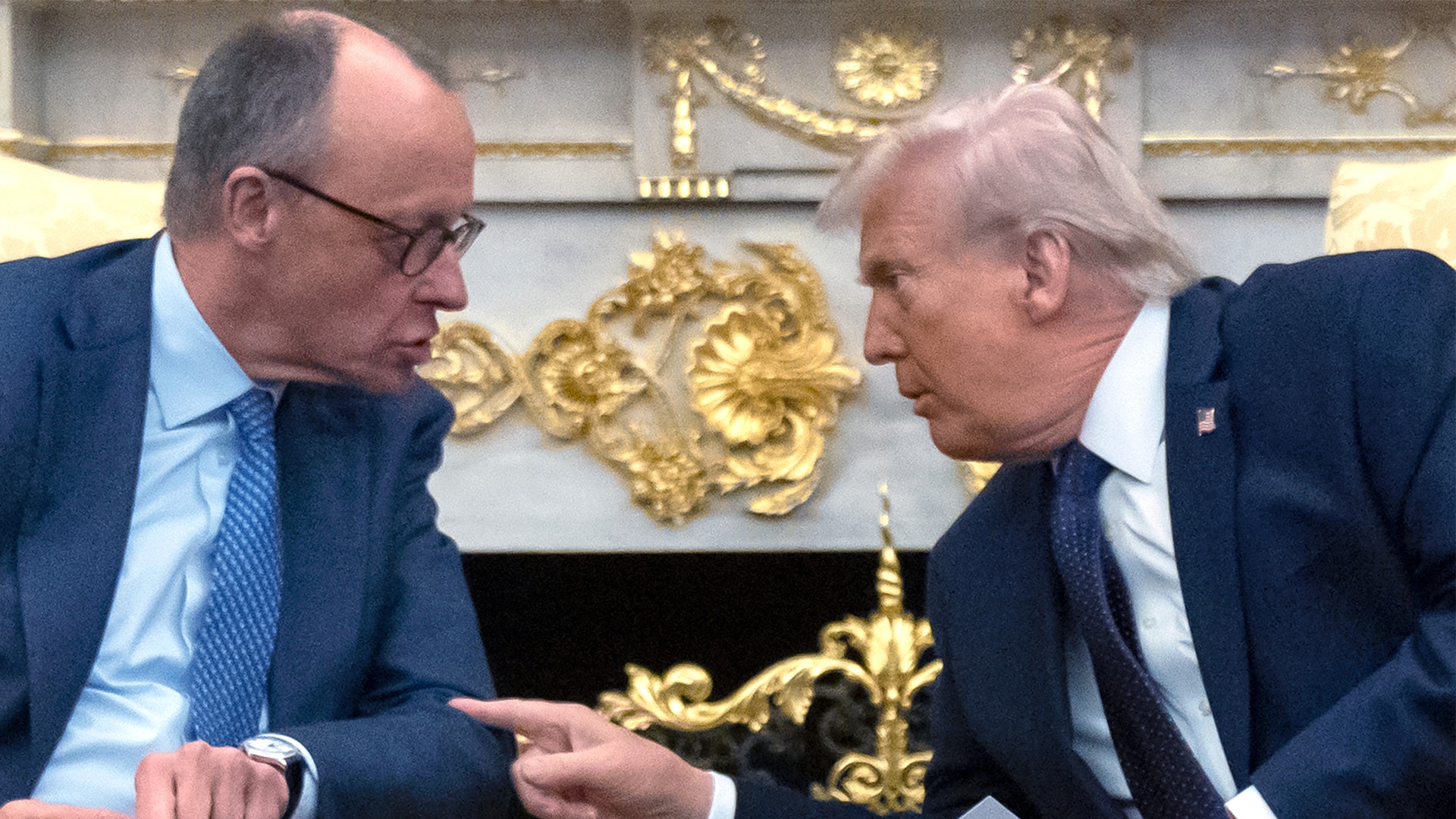 Två män i kostym i samspråk i ett elegant rum med gulddekorationer