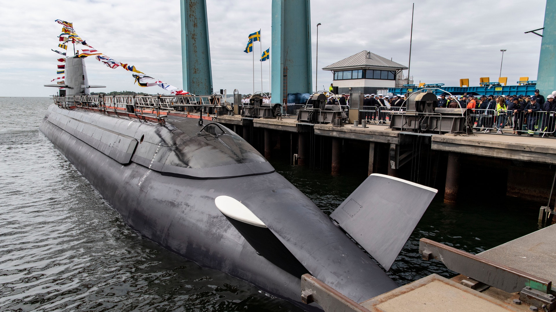 En ubåt dockat vid en pir med människor samlade på kajen.