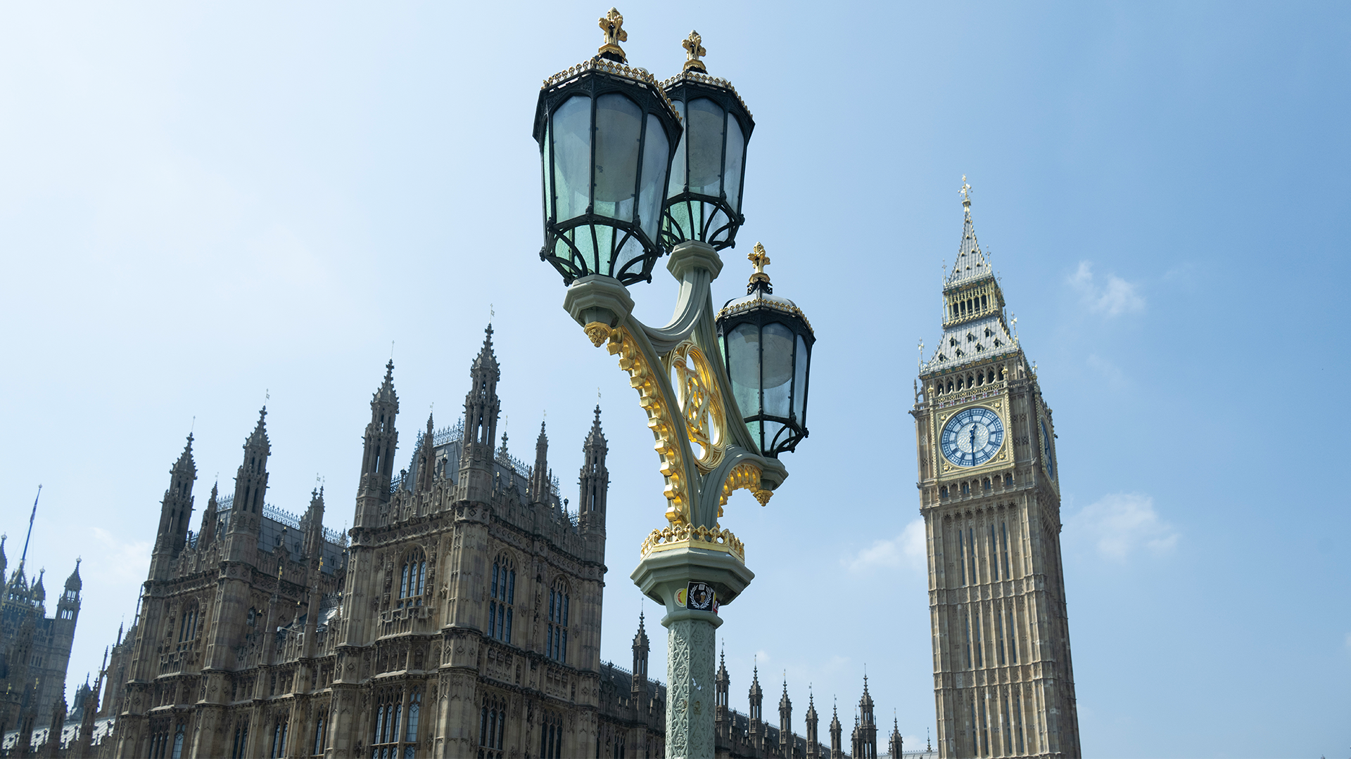 Gatlampa framför Big Ben och Parlamentshuset i London under blå himmel