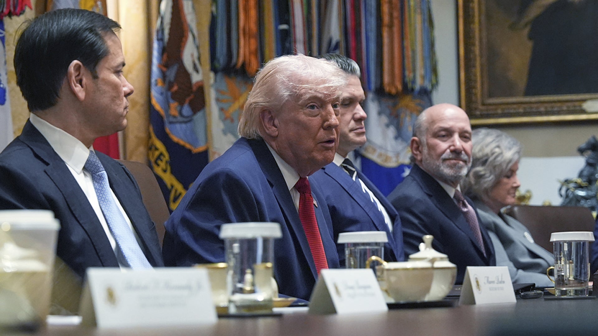 Män i kostym sitter vid ett mötesbord under ett officiellt möte