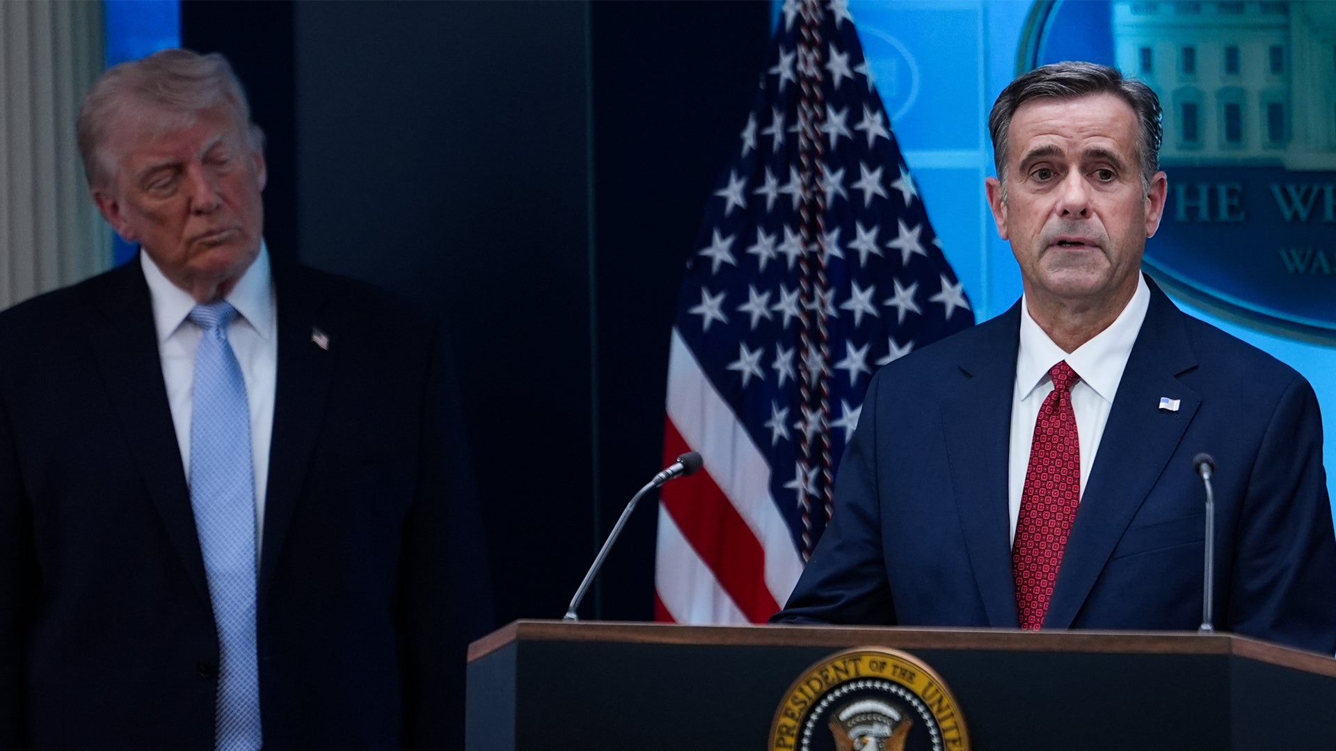 Två män i kostym vid ett presidentiellt podium framför en amerikansk flagga under en officiell presskonferens.