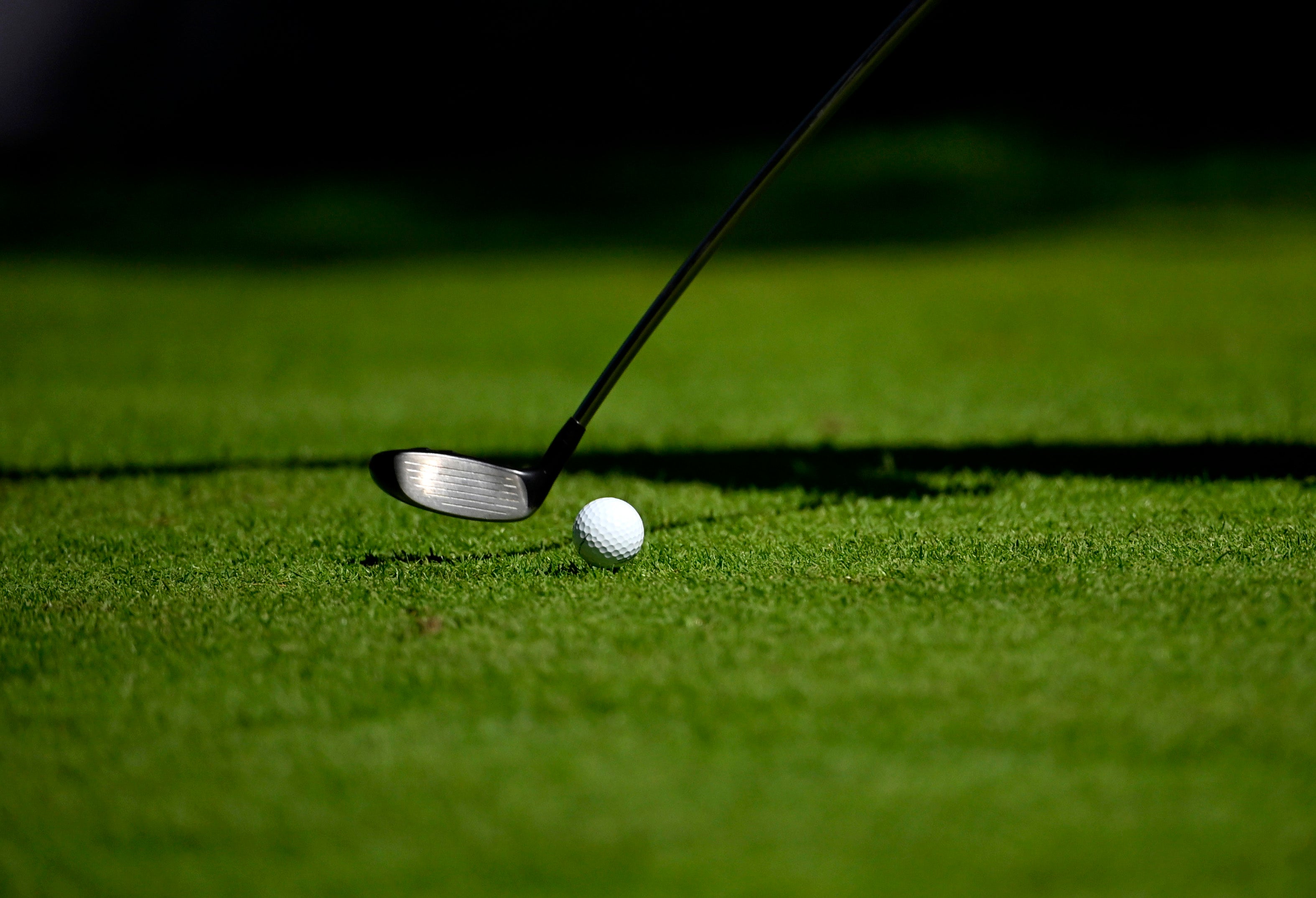 Golfklubba och golfboll på en grön gräsmatta.