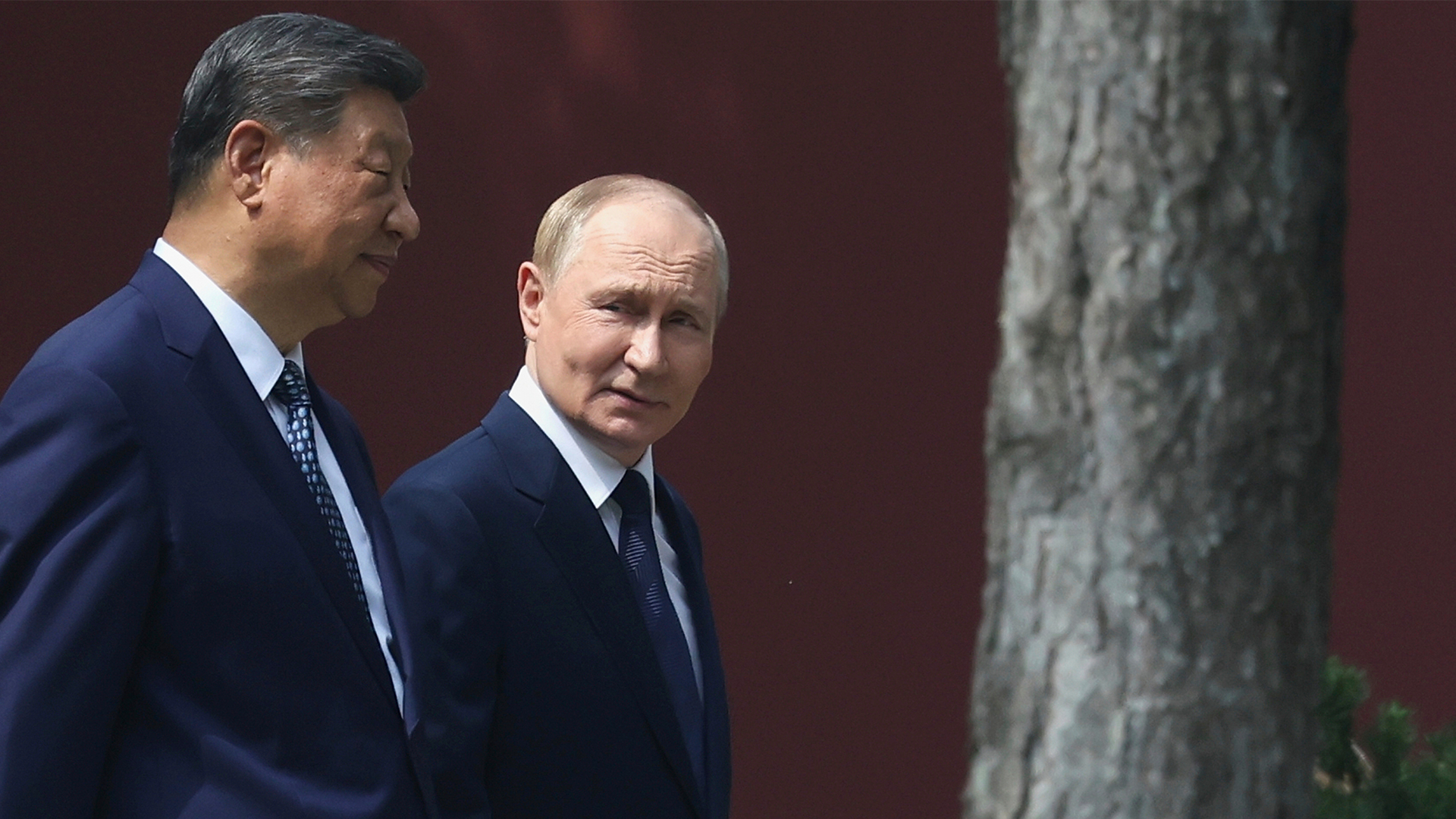 Xi Jinping och Vladimir Putin står bredvid varandra framför en röd vägg. Båda är klädda i mörka kostymer.