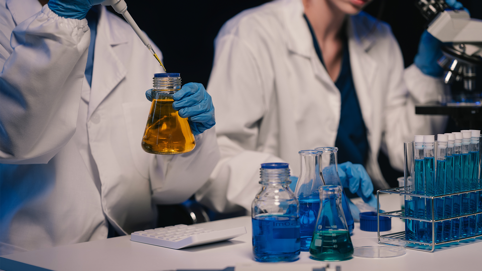 En genrebild på forskare som håller på att ta fram ett nytt läkemedel. I vita rockar sitter de vid ett bord med olika läkemedel och pimpetter.