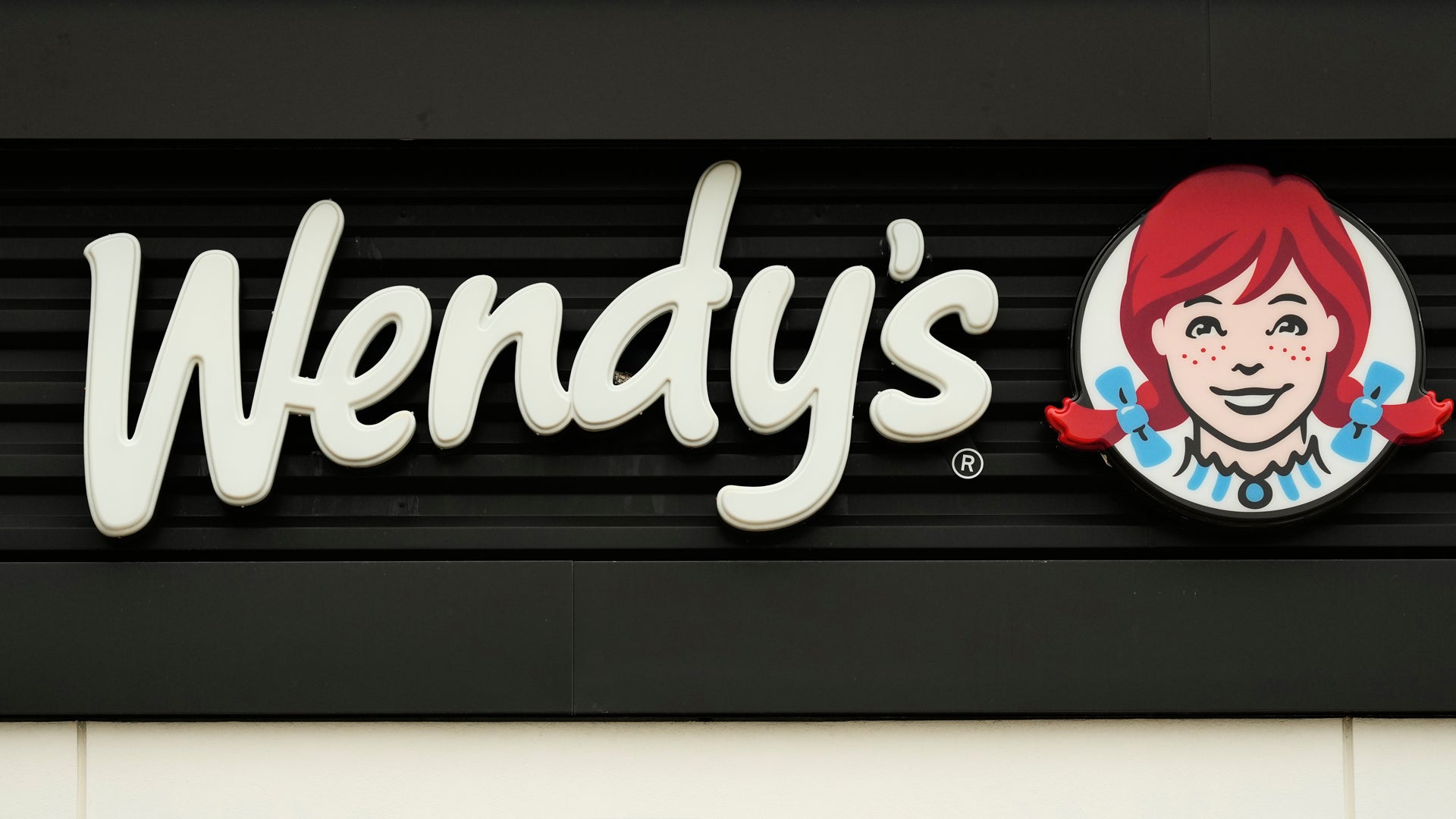 Wendy's logotyp med texten Wendy's i vit stil och varumärkesikonen föreställande en flicka med rött hår och blå örhängen
