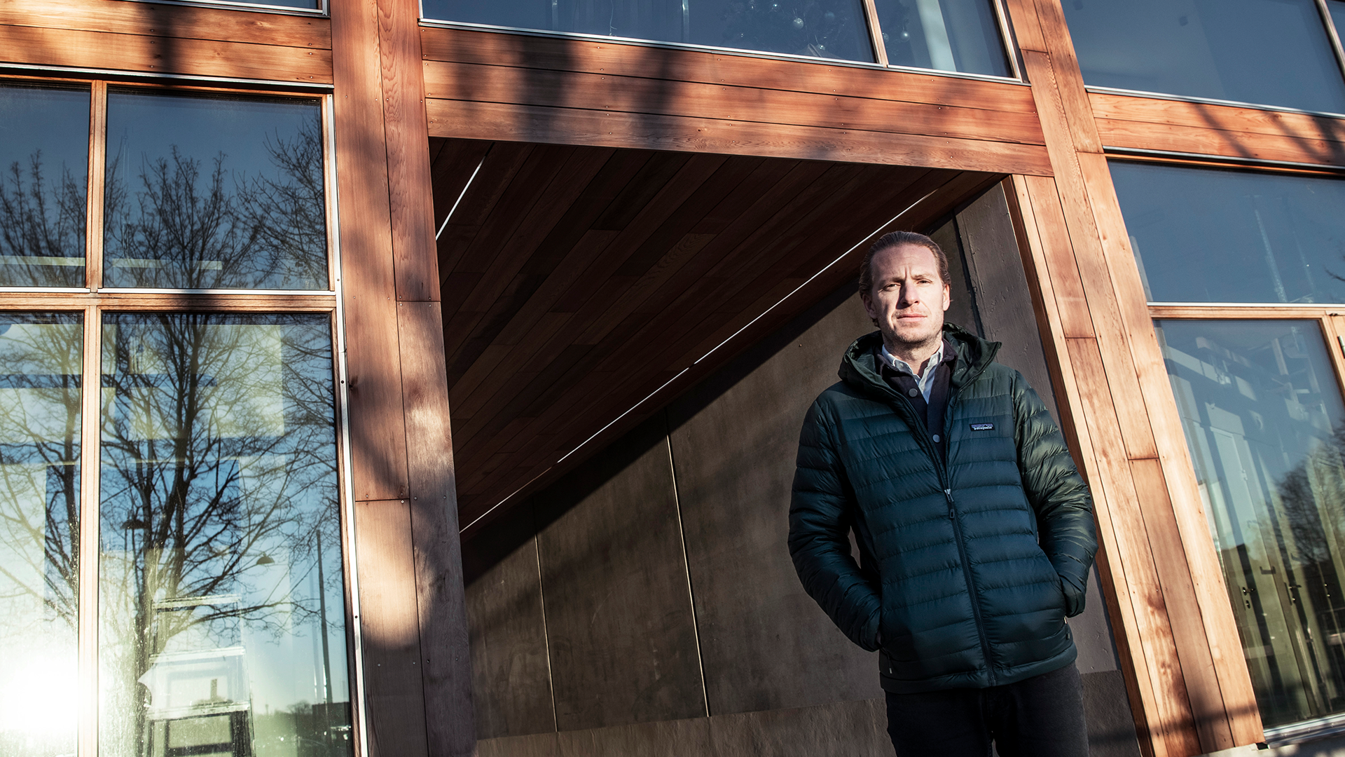 Oscar Engelbert står framför träpanelerna av hans bostäder på Gärdet i Stockholm.