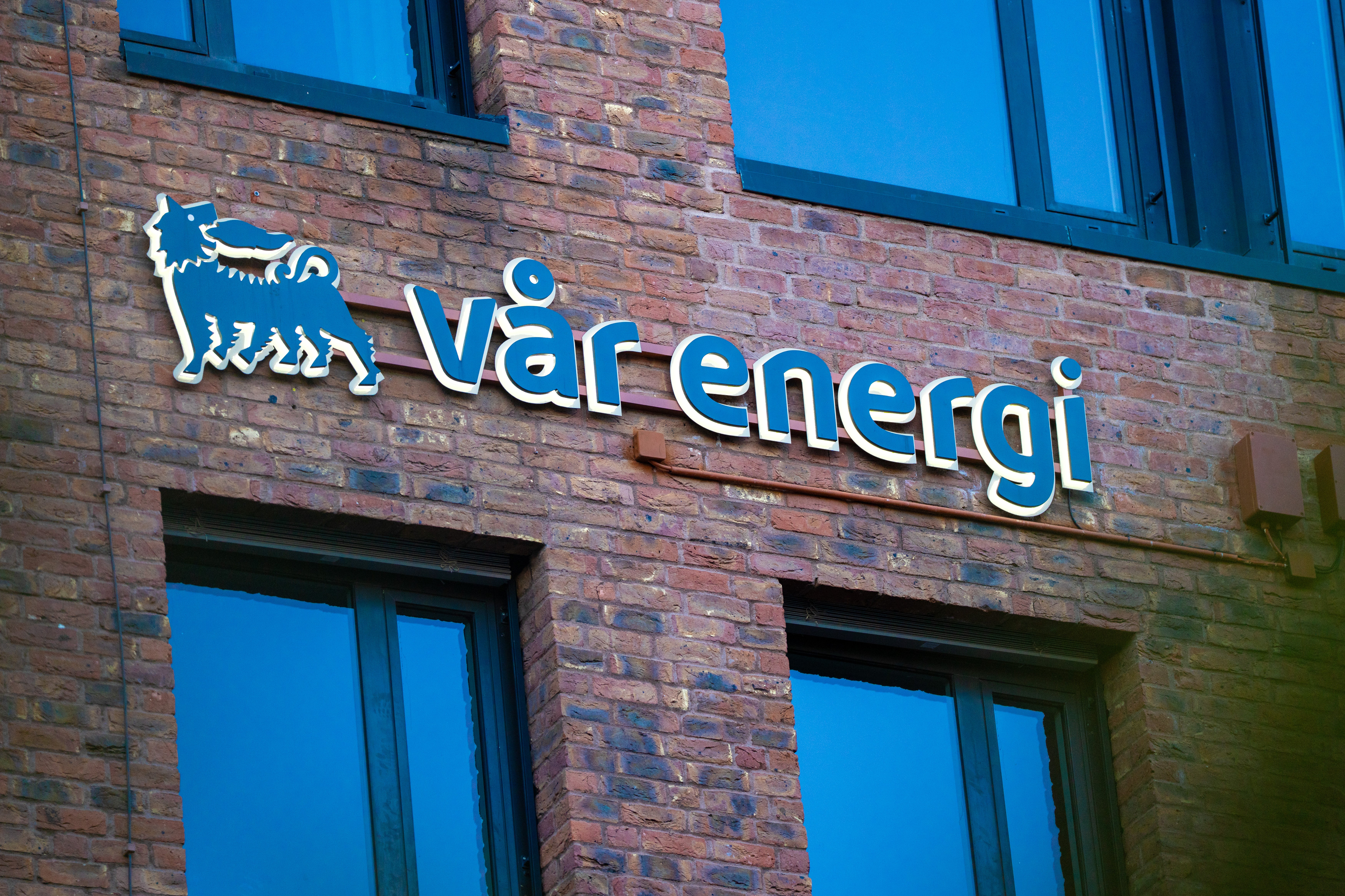 Tegelfasad med blå neonskylt för Värenergis logotyp och namn