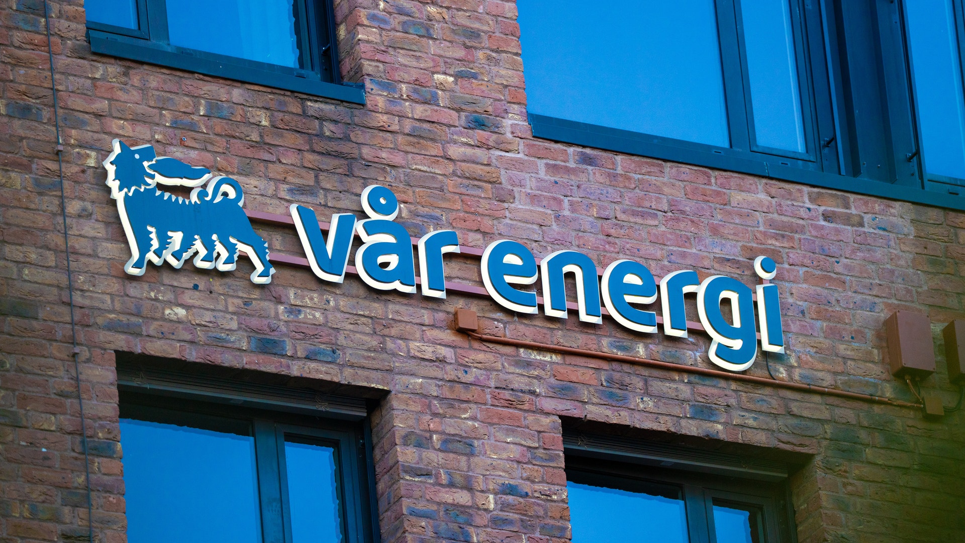 Tegelfasad med blå neonskylt för Värenergis logotyp och namn
