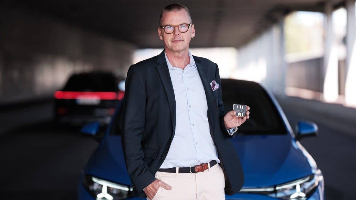 Man i affärskläder står framför en blå bil i ett parkeringshus.