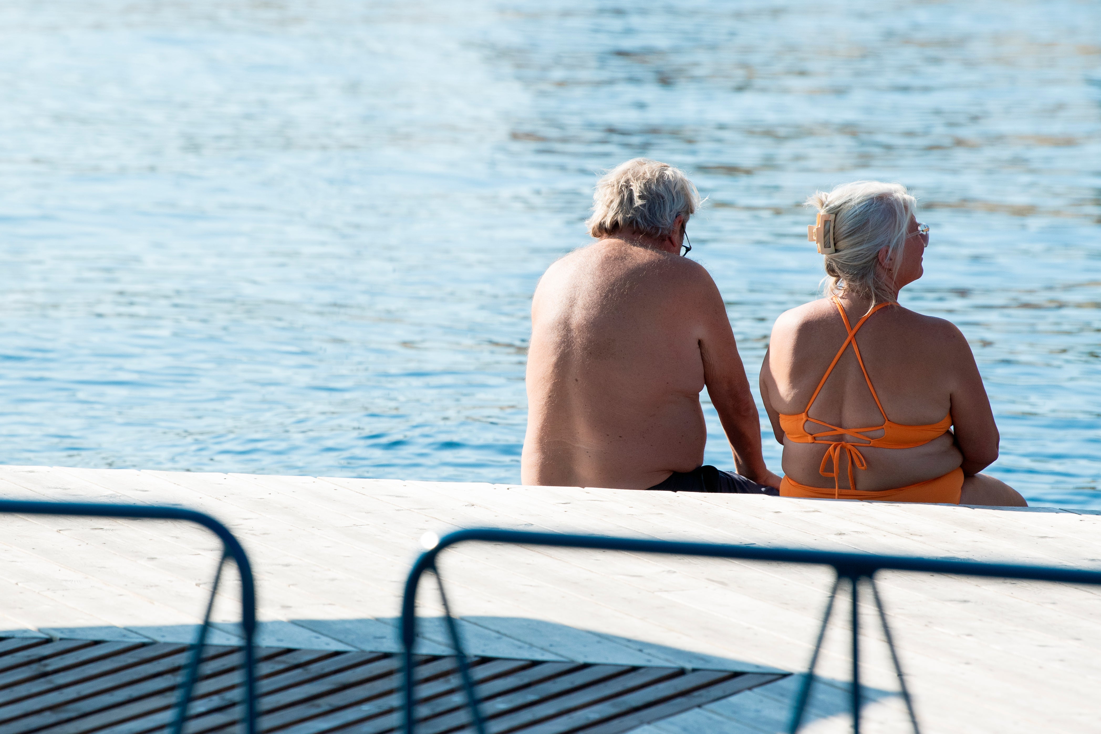 Två äldre personer sitter på en båt och tittar ut över havet.