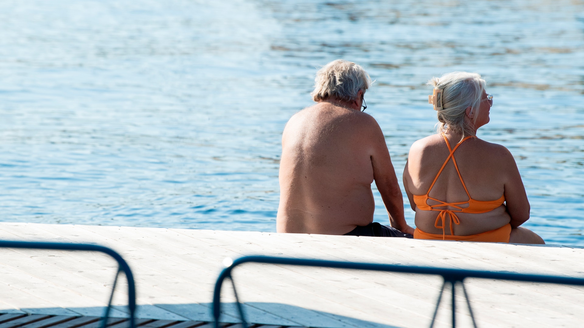 Två äldre personer sitter på en båt och tittar ut över havet.