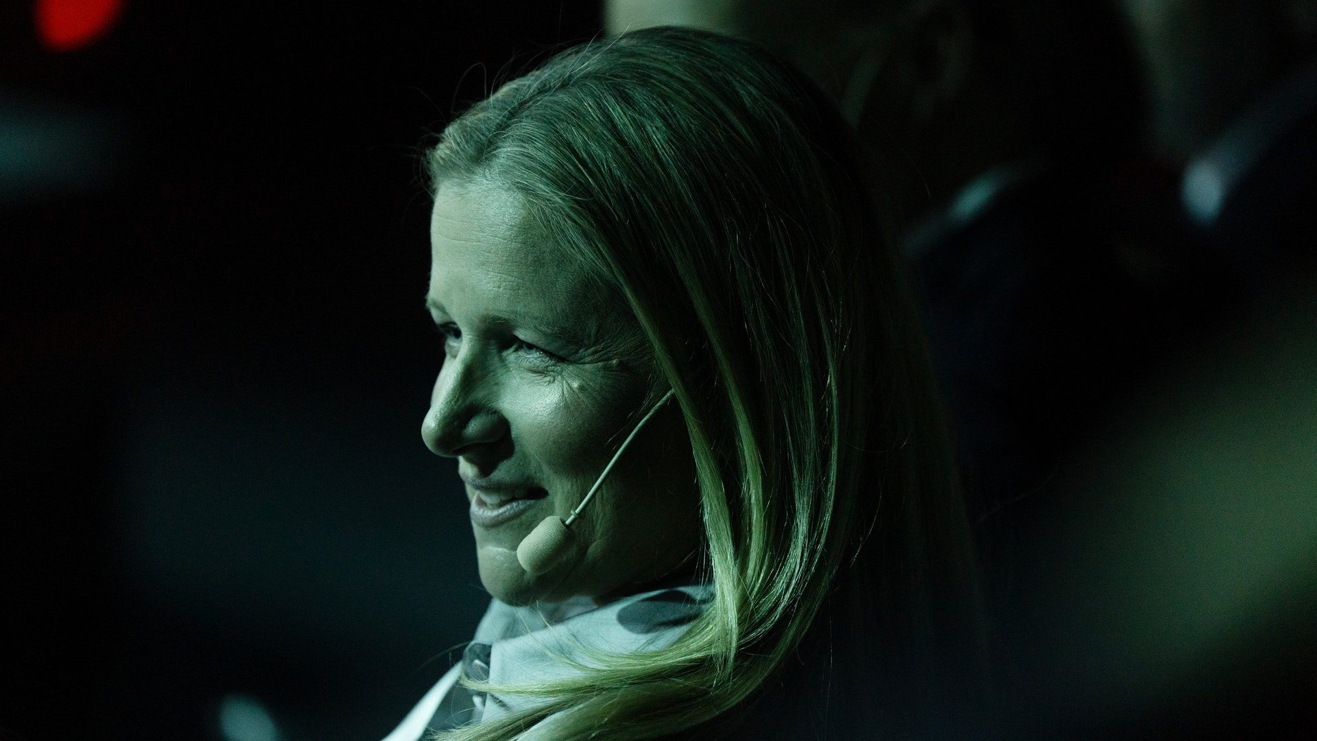 Kvinna i profil med headset-mikrofon på ett evenemang
