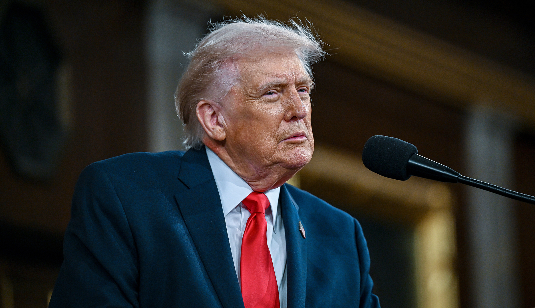 USA:s president Donald Trump i mörk kostym och röd slips talar i en mikrofon.