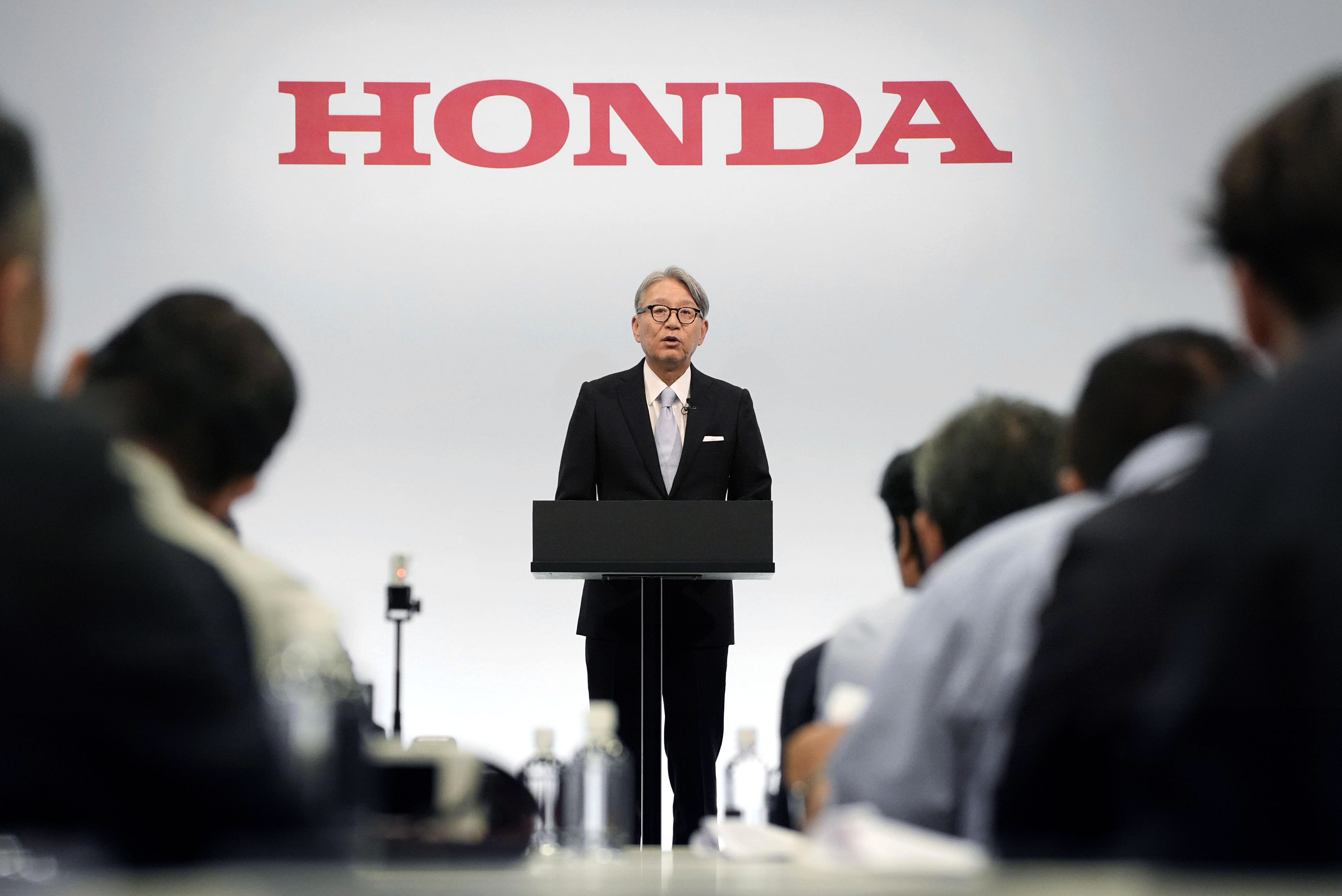 Man i kostym står vid ett podium under Honda-loggan och presenterar för en publik.