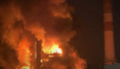 En stor brand med orange och gula flammor som slår upp mot mörk himmel på natten.