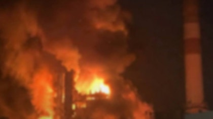 En stor brand med orange och gula flammor som slår upp mot mörk himmel på natten.