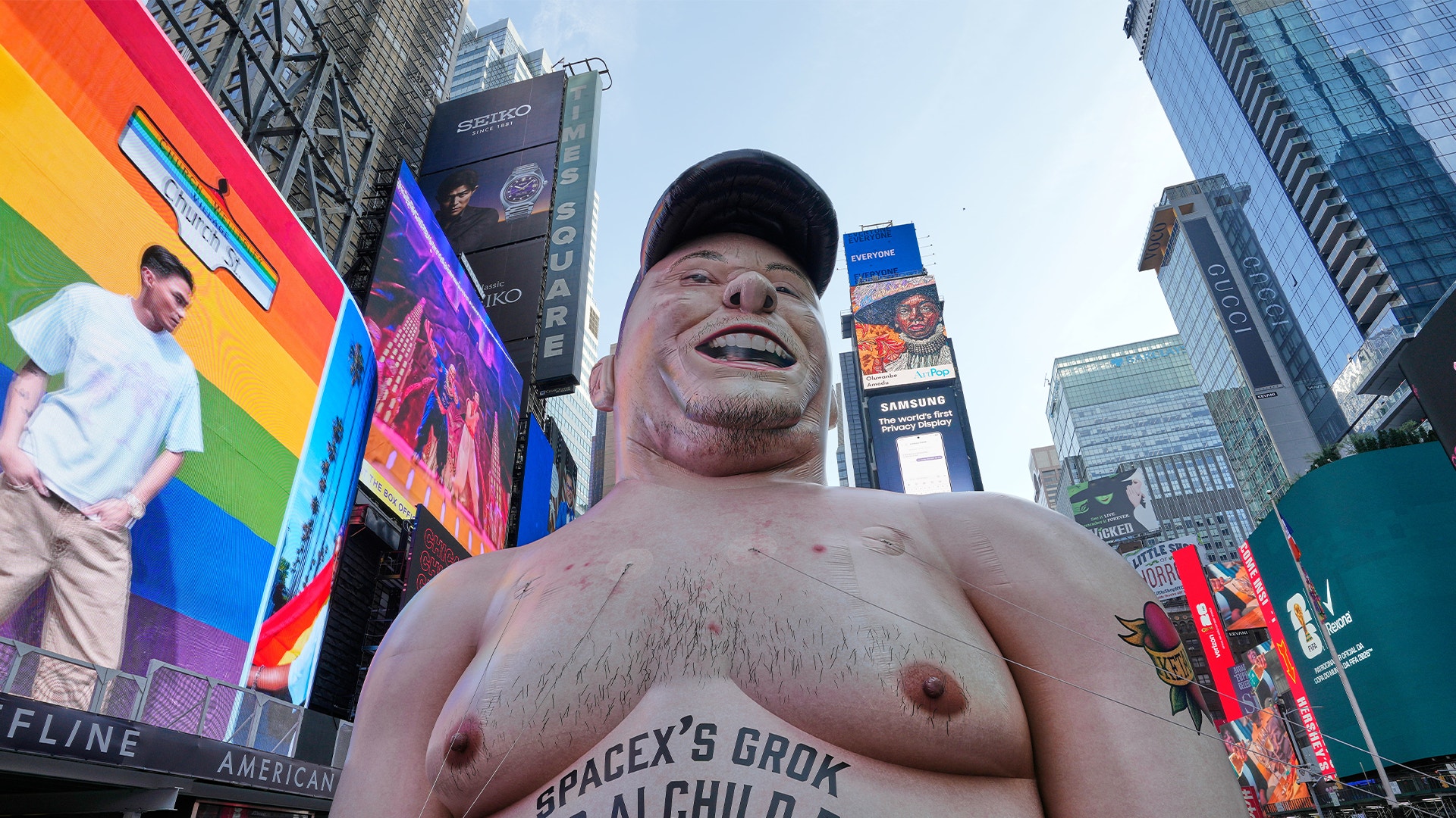 En stor uppblåsbar figur på Times Square i New York, omgiven av höga byggnader och digitala reklamskärmar.