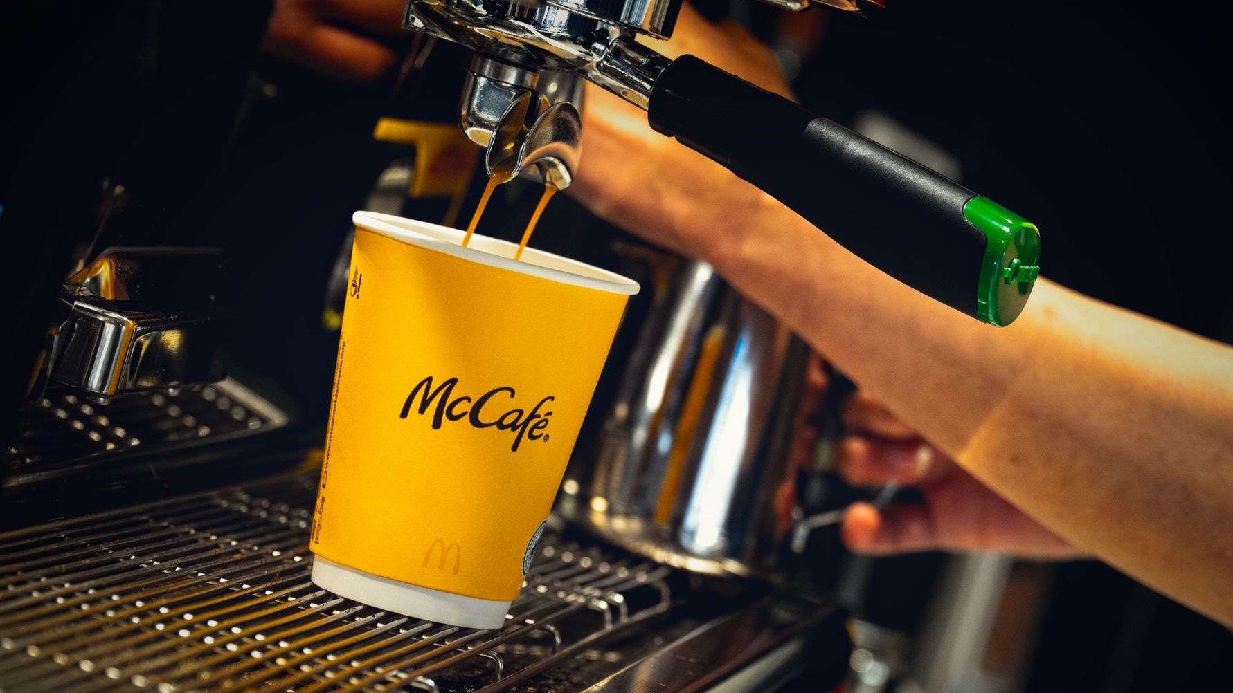 Kaffe hälls från en espressomaskine in i en gul McCafé-kopp.