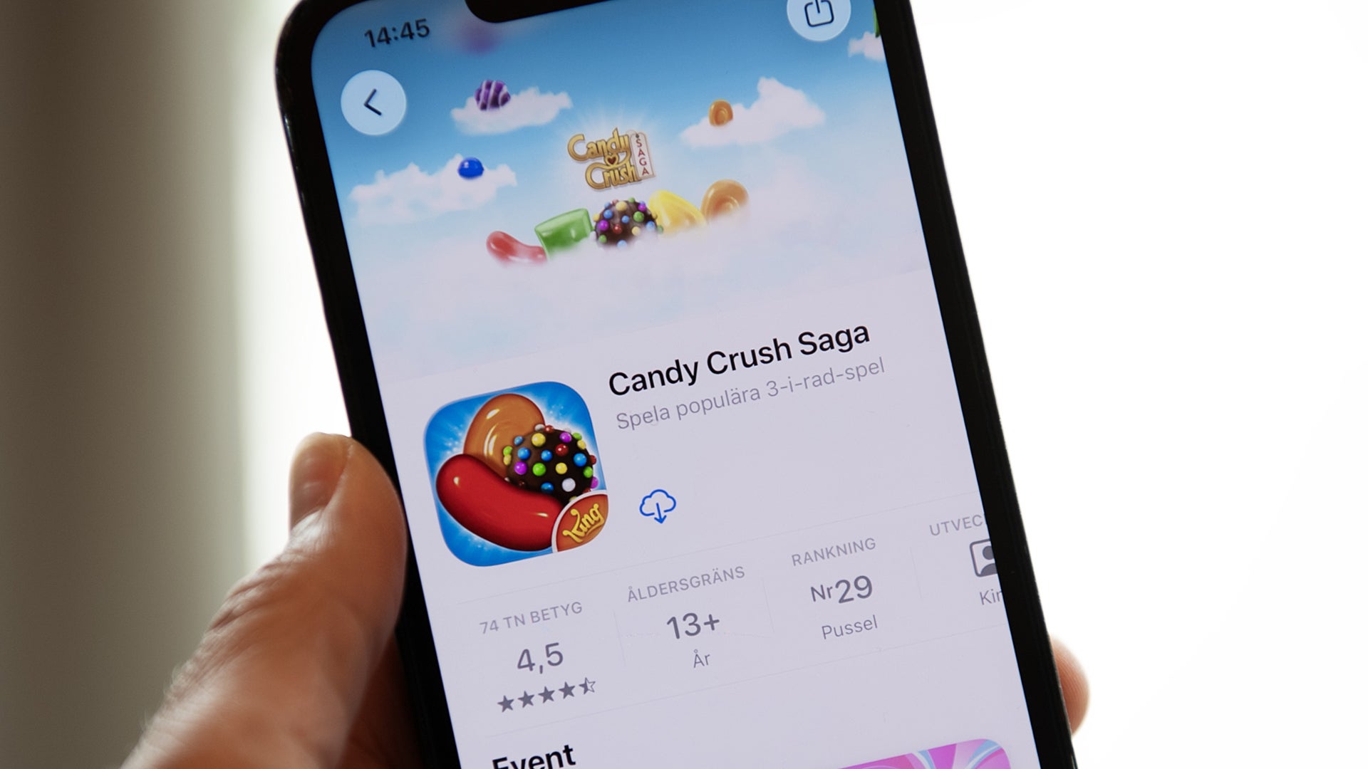 En hand håller en mobiltelefon där spelet Candy Crush Saga visas i App Store.