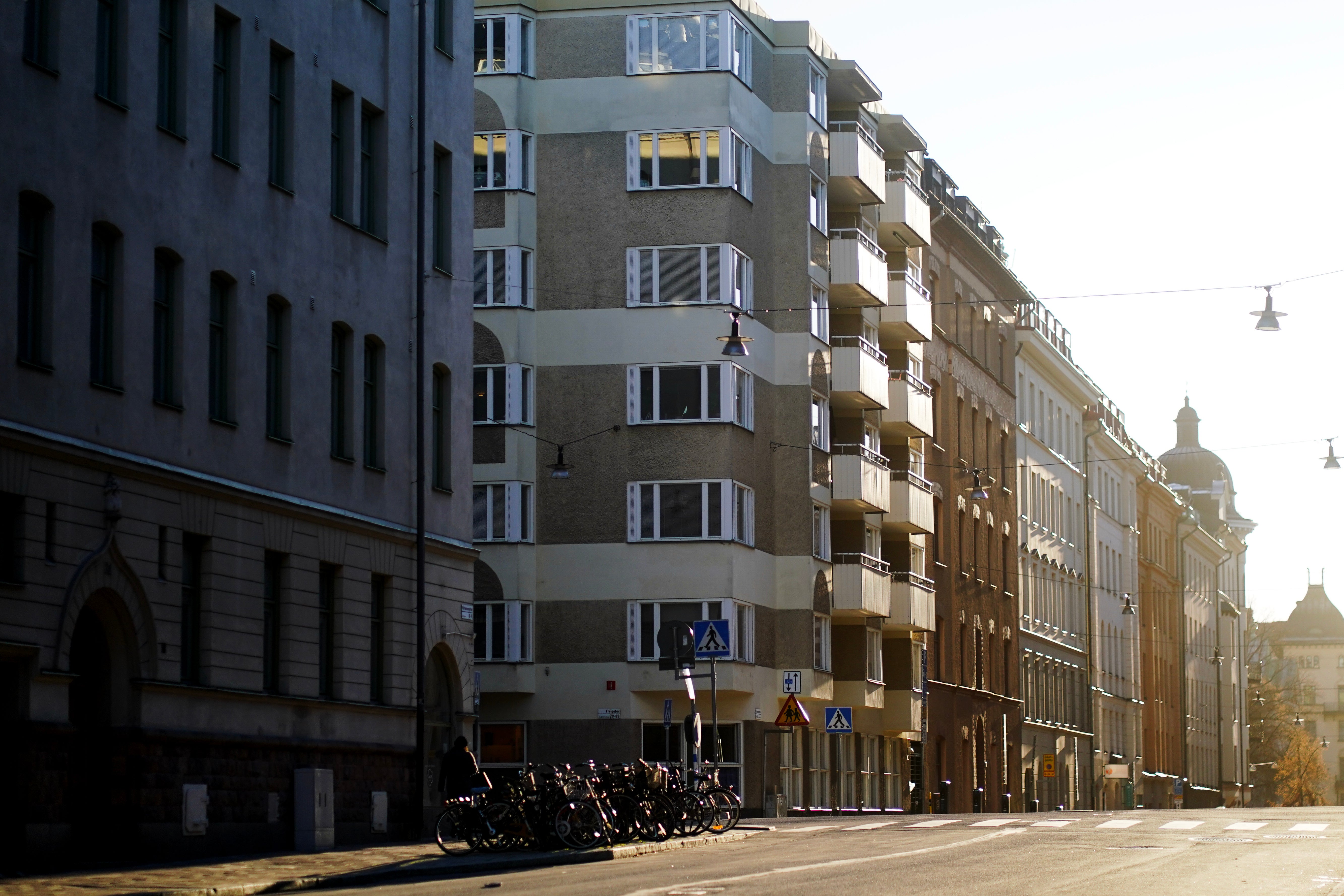 Stadsgata med blandade bostadshus från olika epoker, från klassiska historiska byggnader till moderna flerbostadshus.