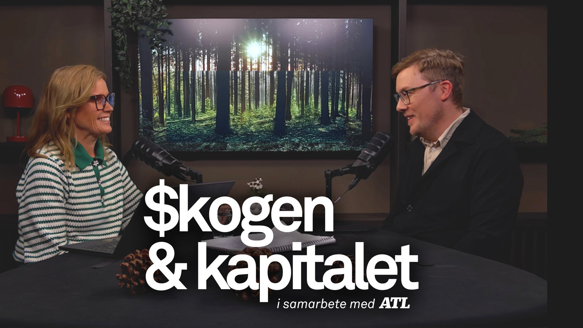Två personer sitter vid ett bord och samtalar framför en stor skärm som visar en grön skog. Texten på bilden lyder 'Skogen & kapitalet - i samarbete med ATL'.