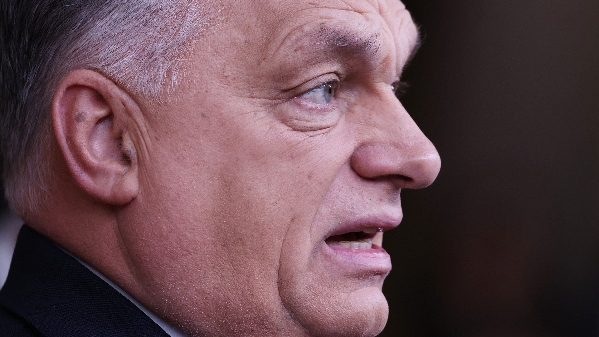 Profilbild av en äldre man med grått hår mot mörk bakgrund