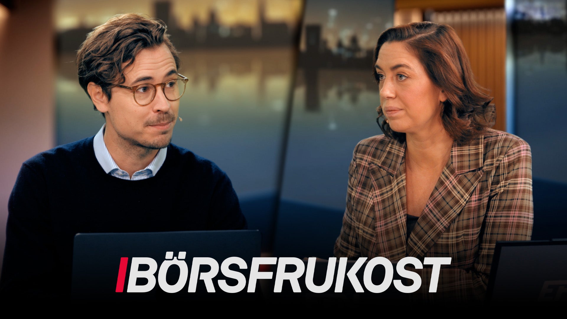 Två personer i samtal under ett podcastprogram. En man med glasögon och en kvinna sitter mittemot varandra med en studio i bakgrunden.