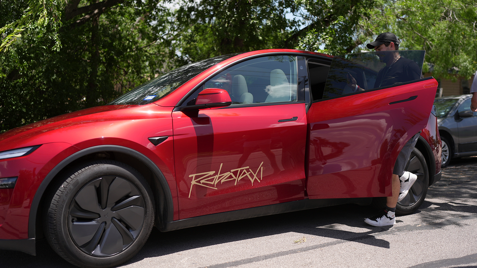 En röd robottaxi av Tesla. En man kliver in i baksätet, på en bil som inte har en mänsklig förare.