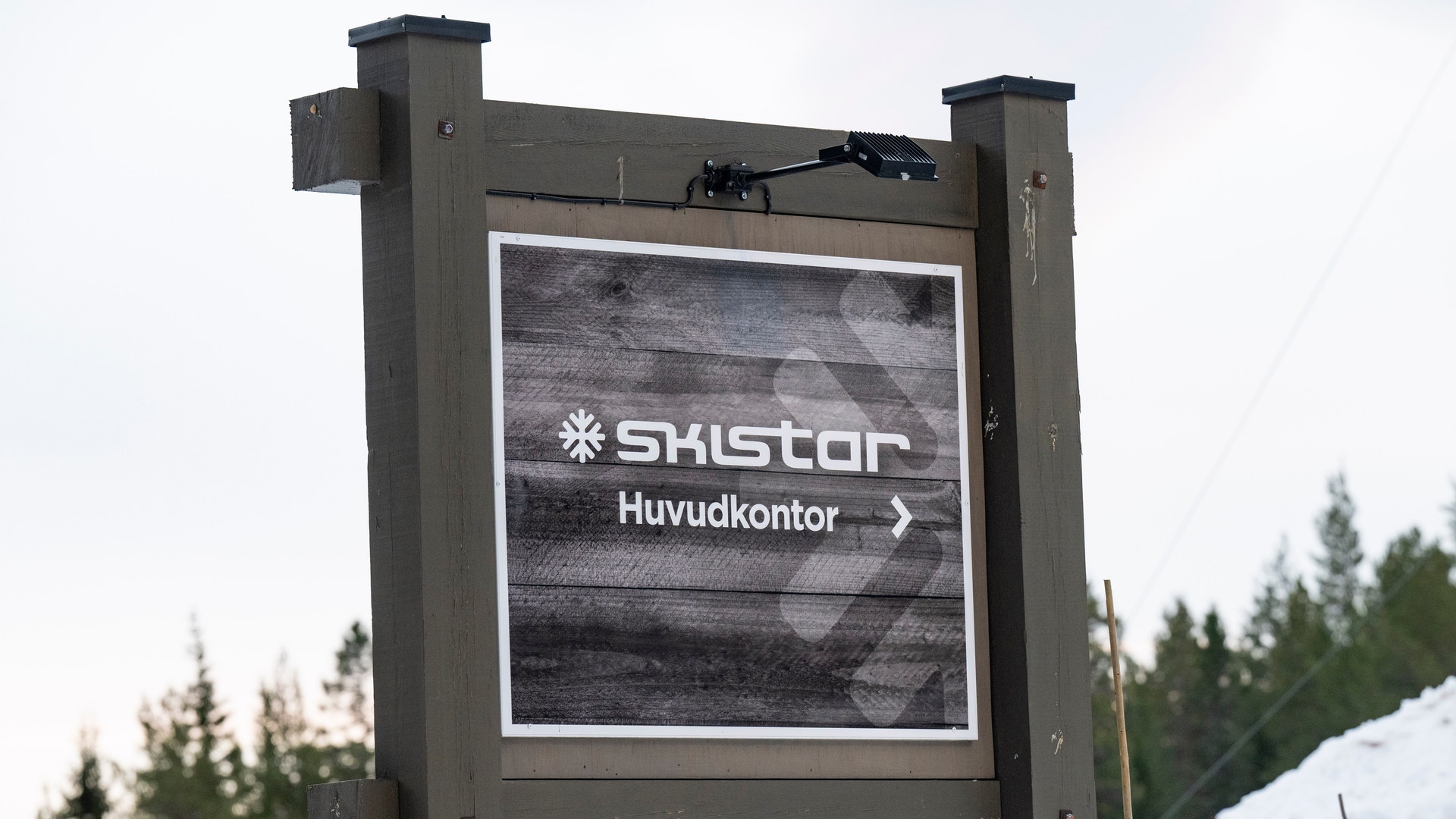 En skylt med texten "Skistar Huvudkontor" och en pil, omgiven av snö och skog.