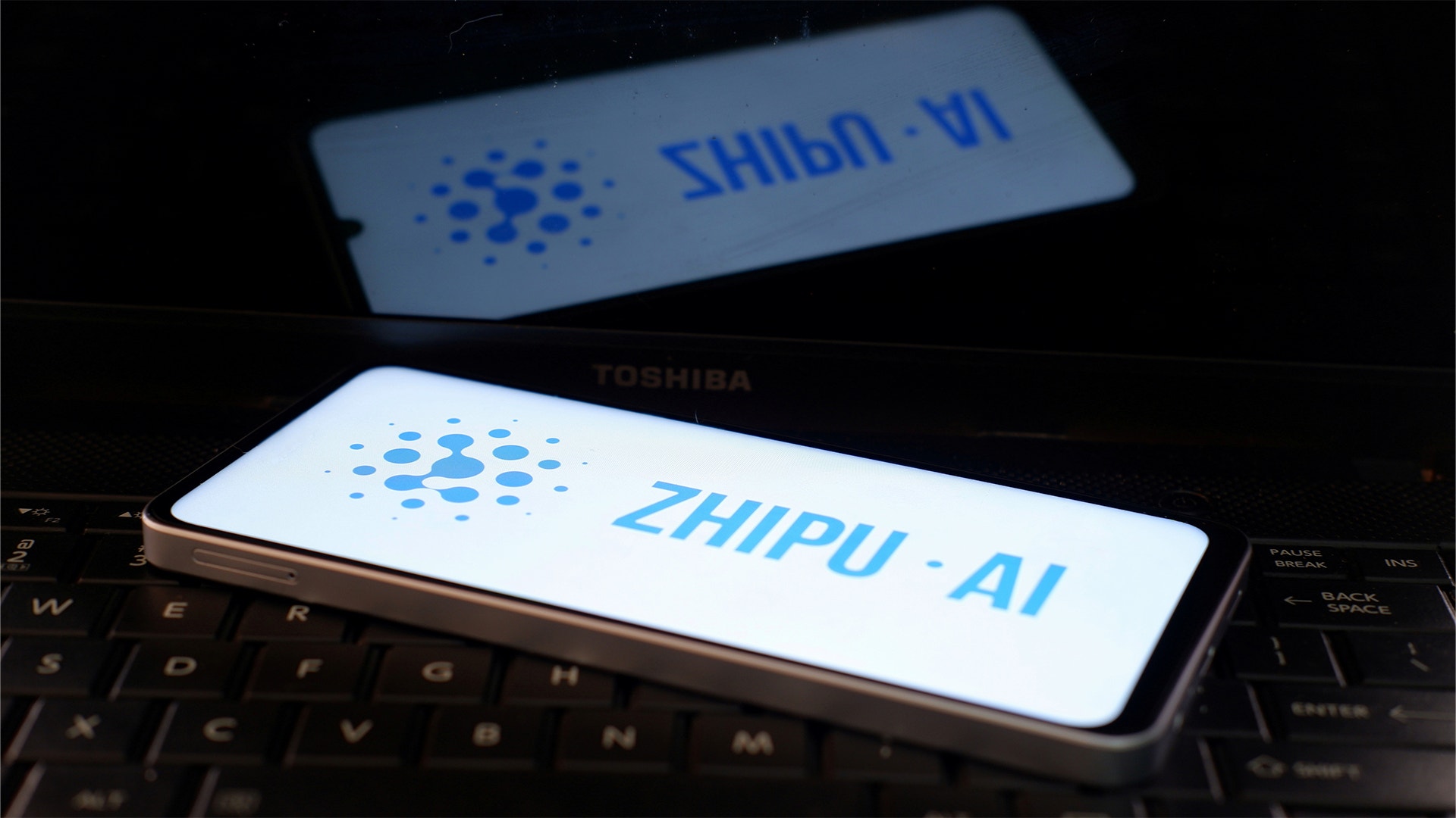 Två smartphones på ett tangentbord visar logotyper för AI-assistenter SHIFU V1 och ZHIPU AI med blå designelement.
