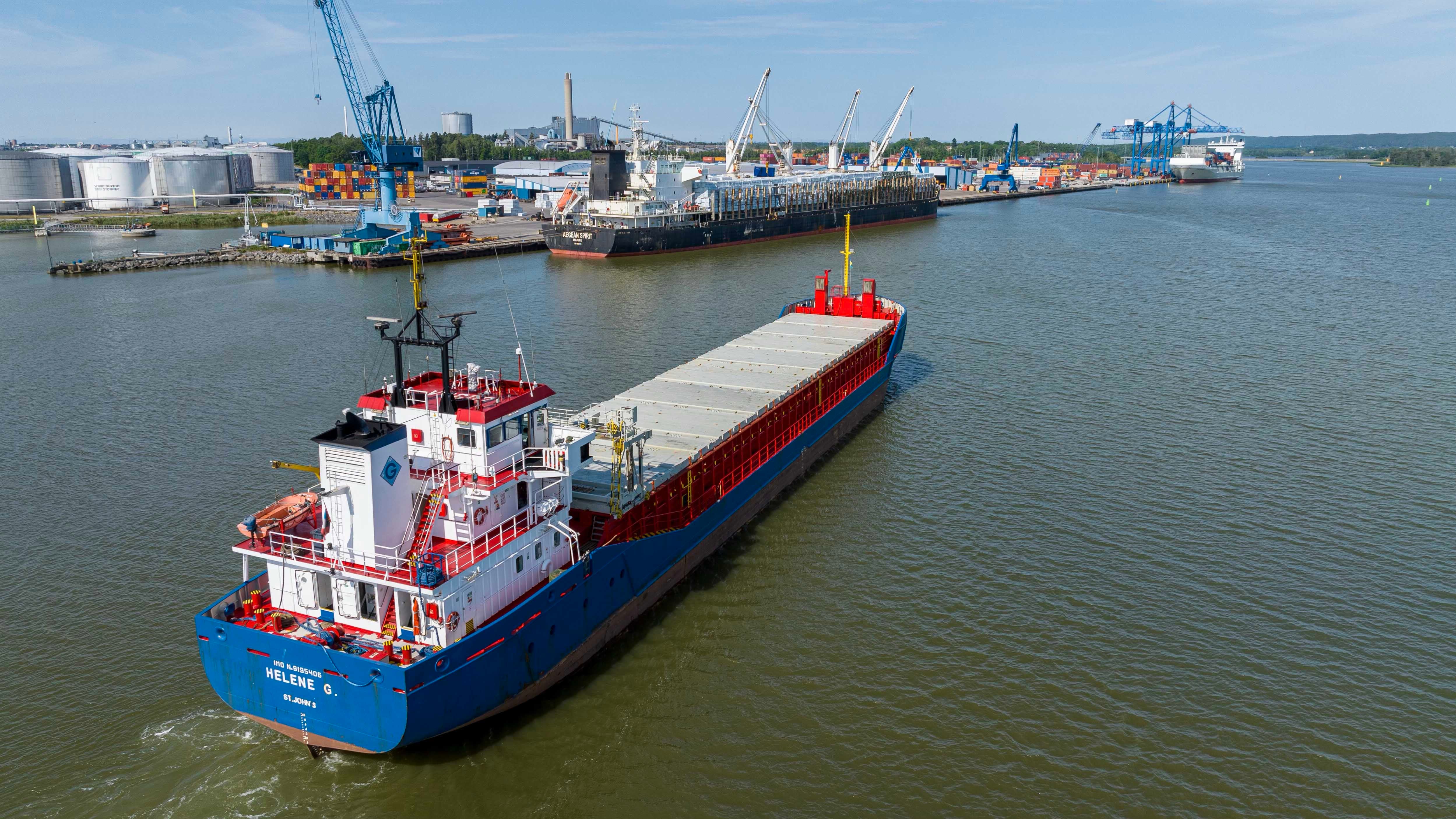 Lastfartyg med röd och blå skrov i hamn