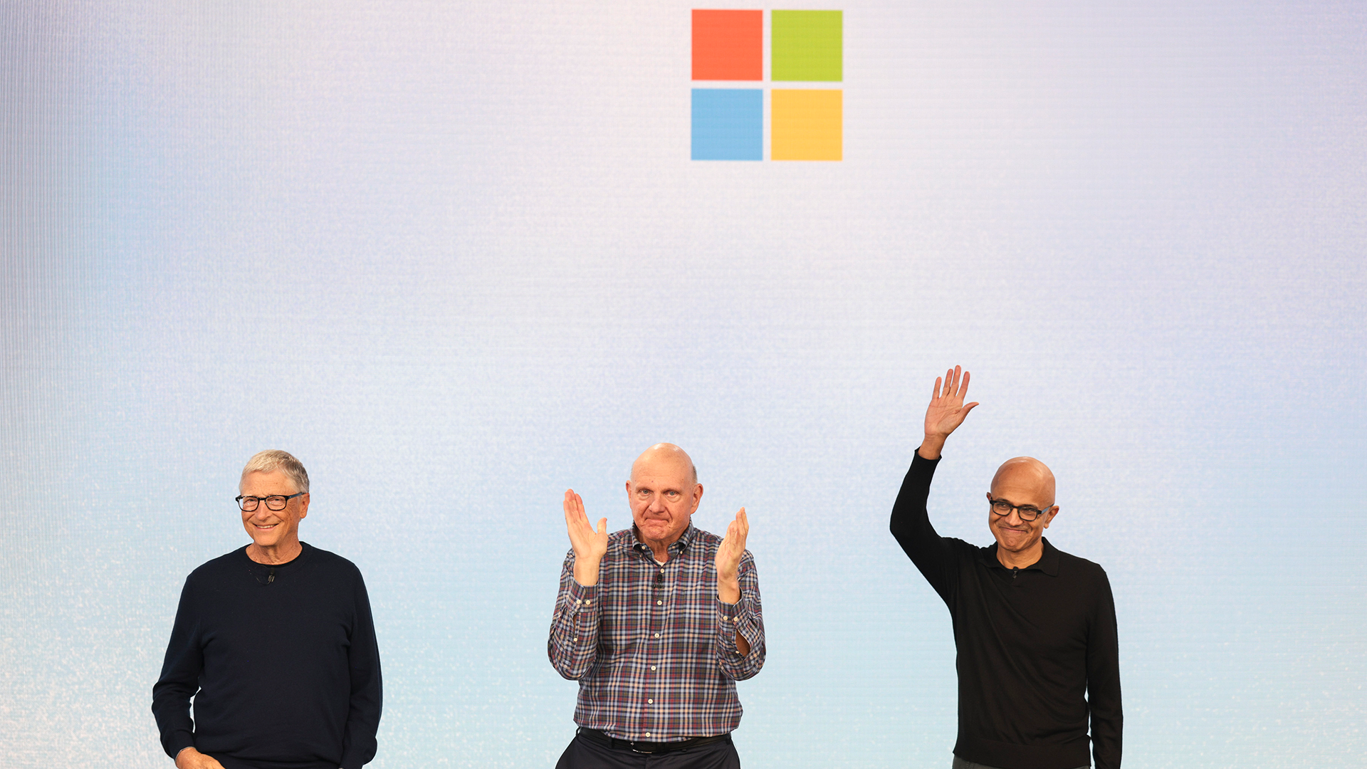 Microsofts logotyp ovanför tre män som gestikulerar