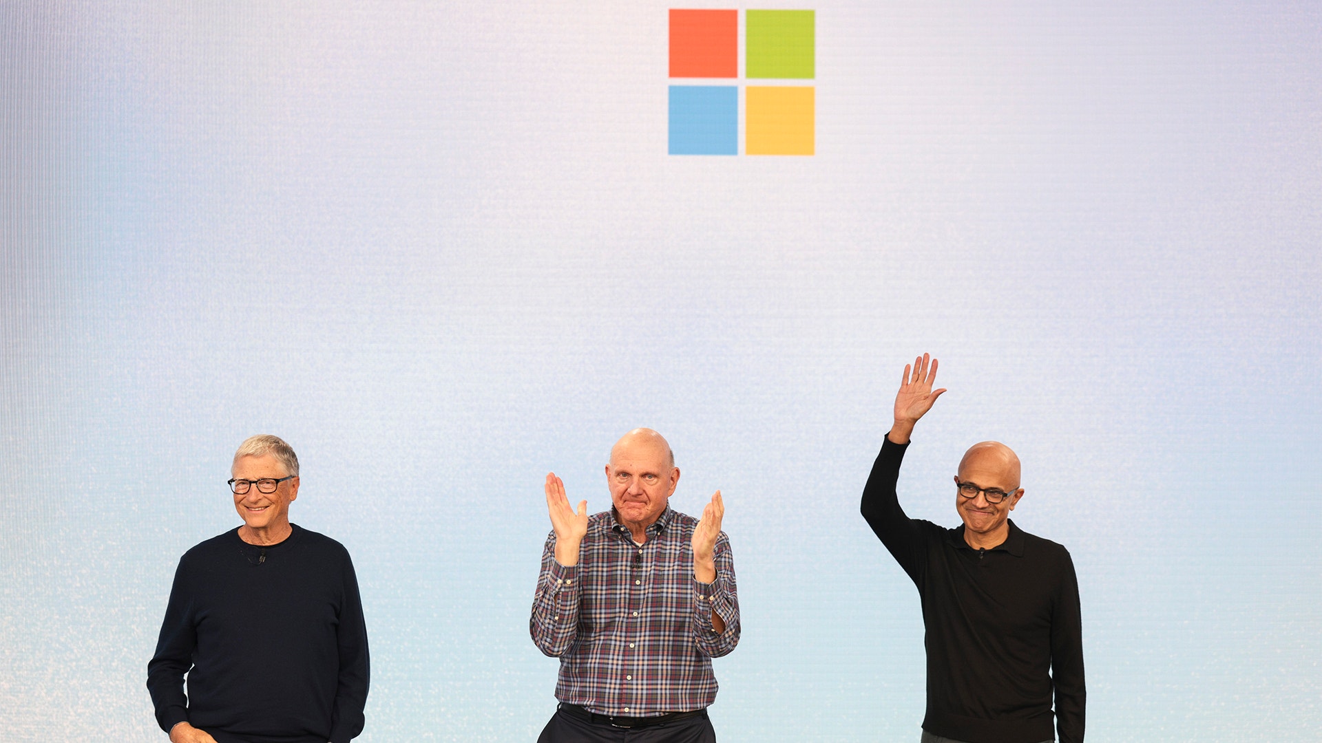 Microsofts logotyp ovanför tre män som gestikulerar