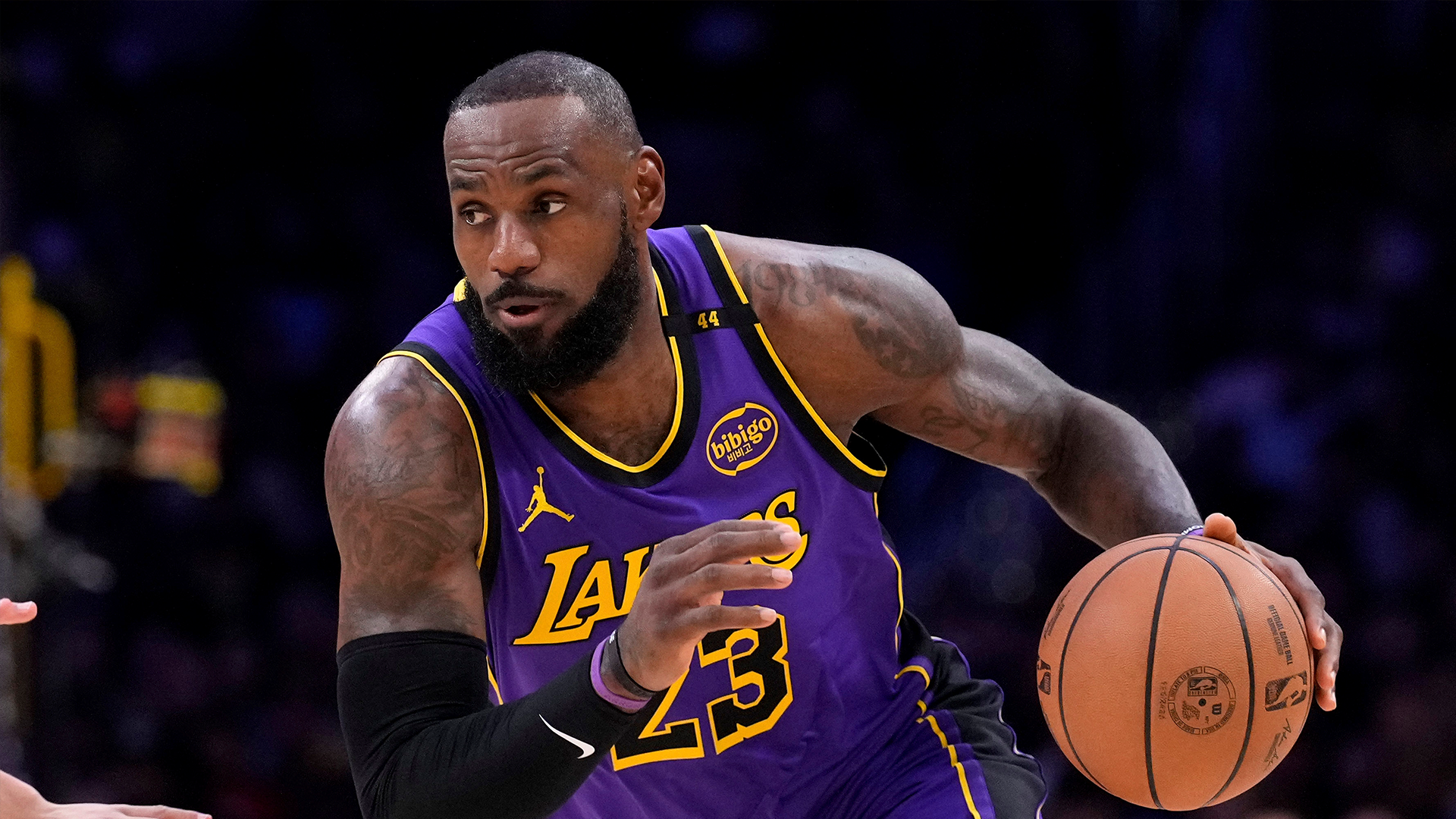 Basketspelare i Los Angeles Lakers lila tröja dribblar med en basketboll under en match.