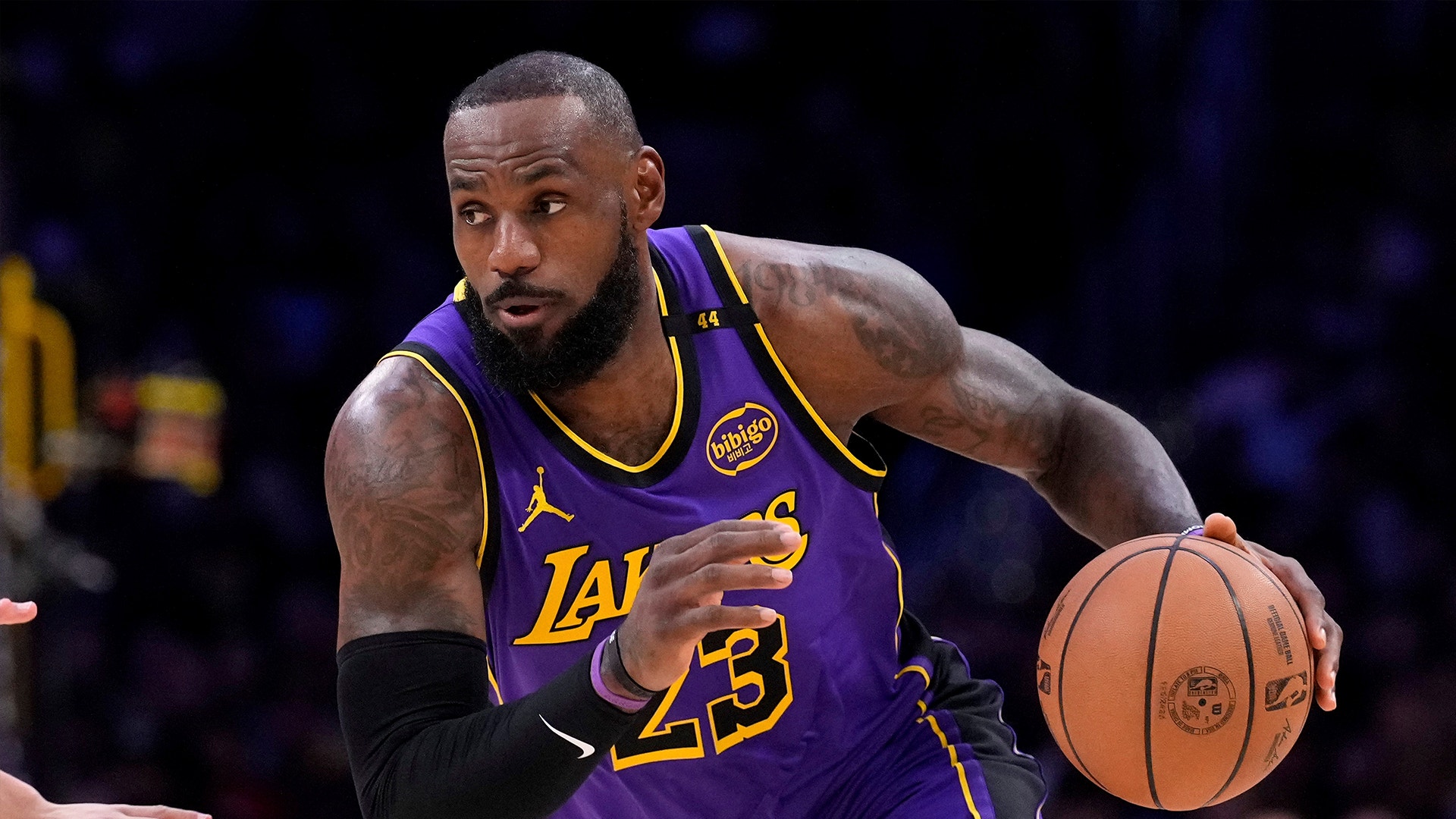 Basketspelare i Los Angeles Lakers lila tröja dribblar med en basketboll under en match.