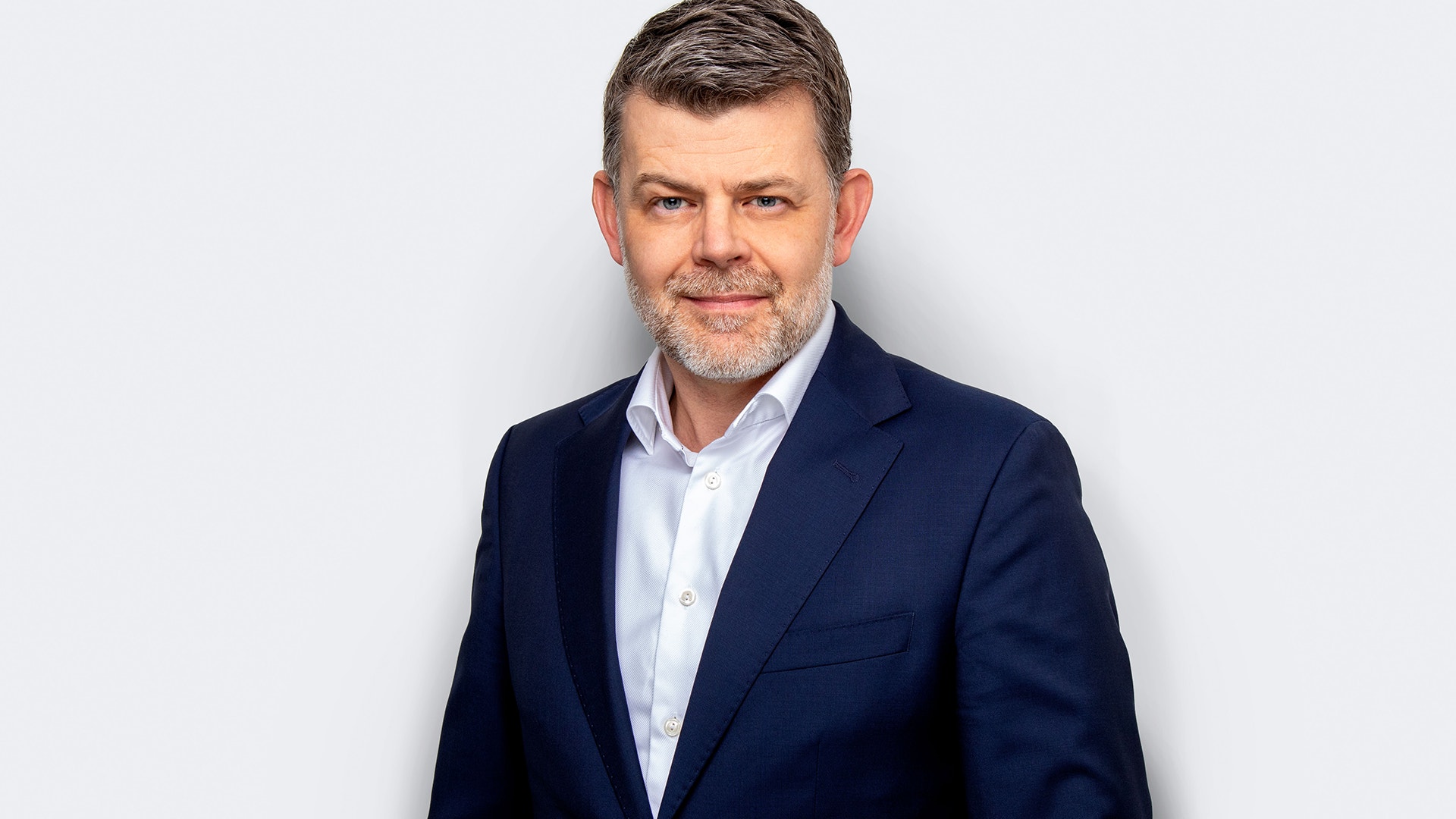 Porträttfoto av en Øyvind Oanes, Morrow Bank i mörkblå kavaj och vit skjorta mot ljus bakgrund