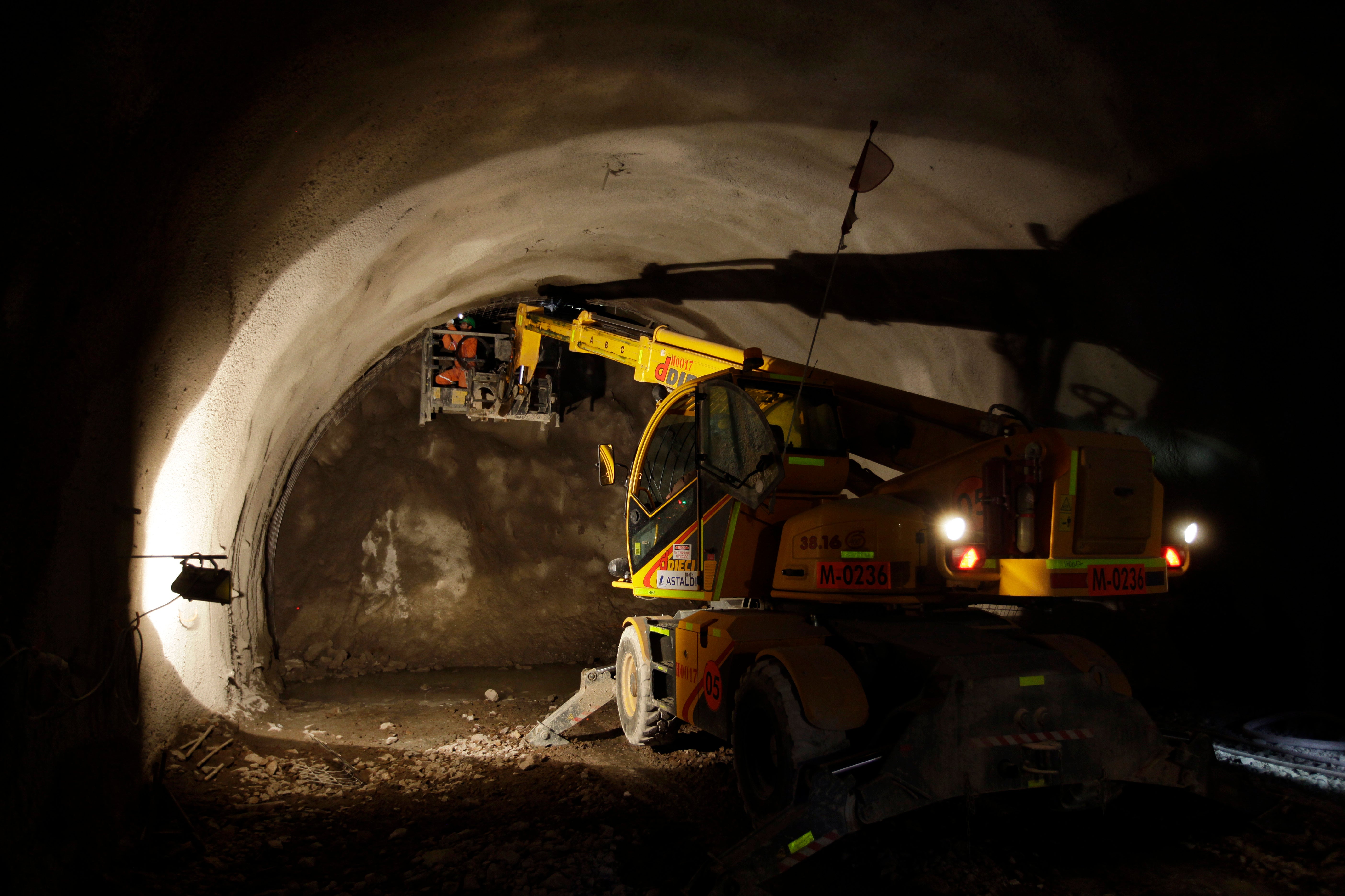 En gul borrmaskin arbetar inne i en upplyst gruvtunnel.