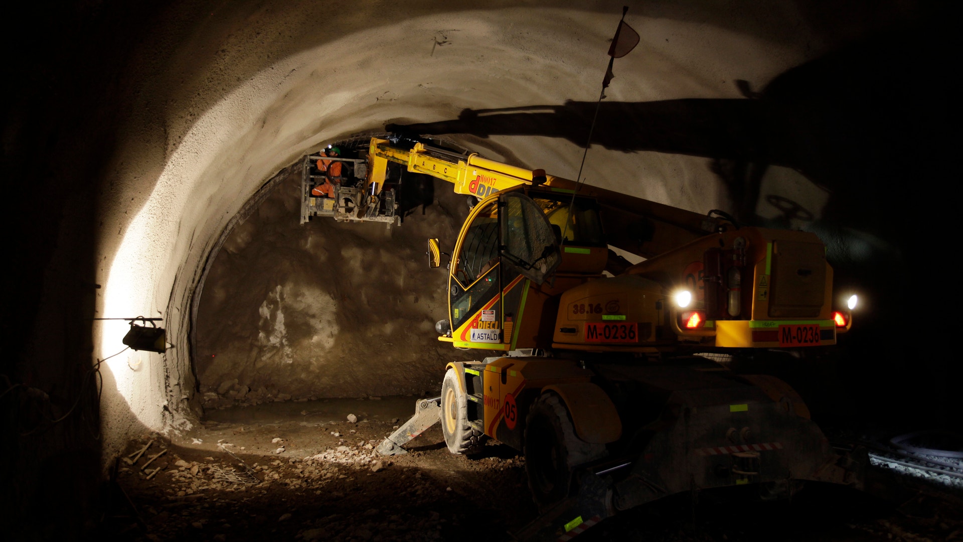 En gul borrmaskin arbetar inne i en upplyst gruvtunnel.
