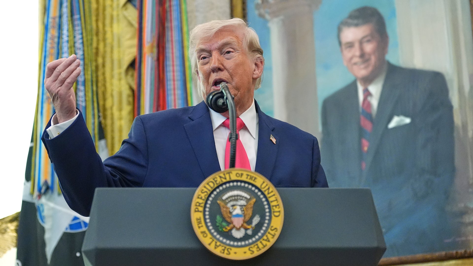 Man i mörk kostym talar vid ett presidentpodium med presidentens sigill.