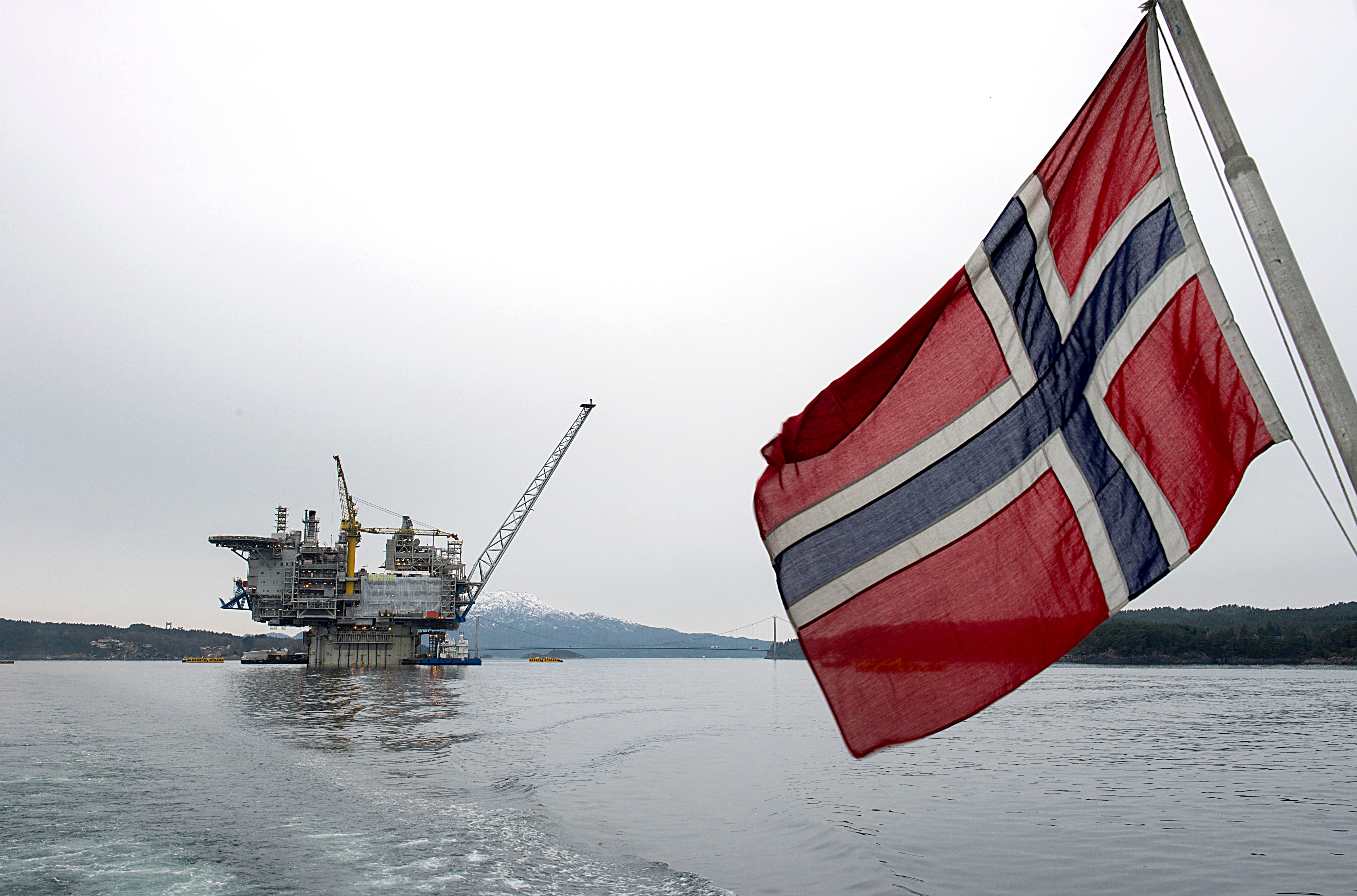 Norsk flagga på havet med en oljeplattform i bakgrunden